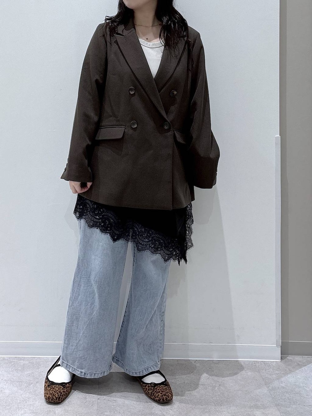 ブルー系のデニムパンツ、ブラウン系のテーラードジャケット、ゴールド系のネックレスを着用したレディースの春コーディネートの4枚目の写真