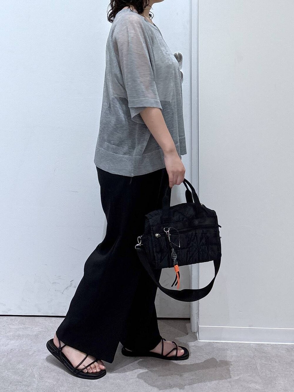 グレー系のニット/セーター、ブラック系のその他パンツ、ブラック系のボストンバッグを着用したレディースの夏コーディネートの2枚目の写真