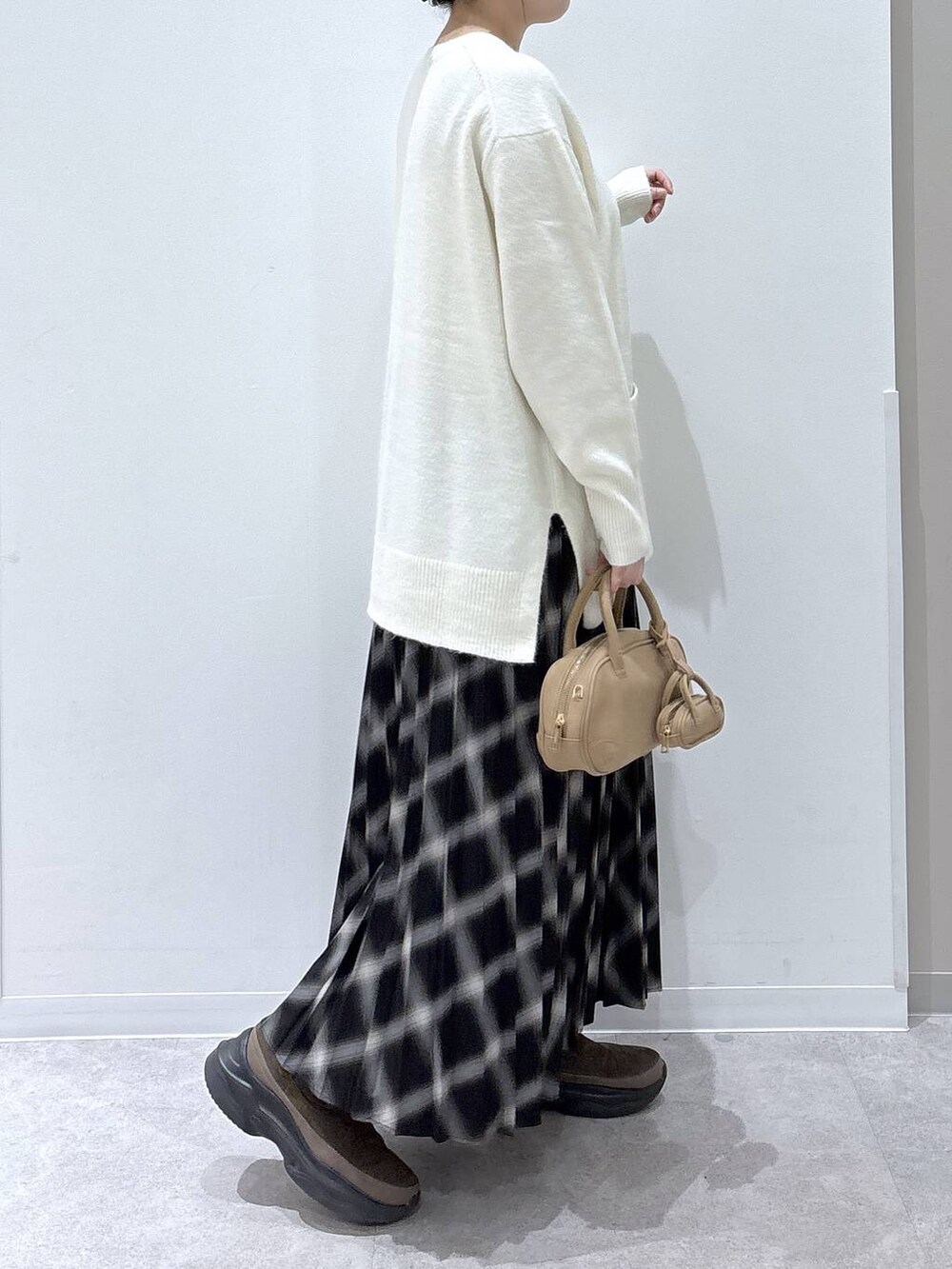 ホワイト系のカーディガン/ボレロ、ブラウン系のブーツ、ブラック系のスカートを着用したレディースの冬コーディネートの3枚目の写真