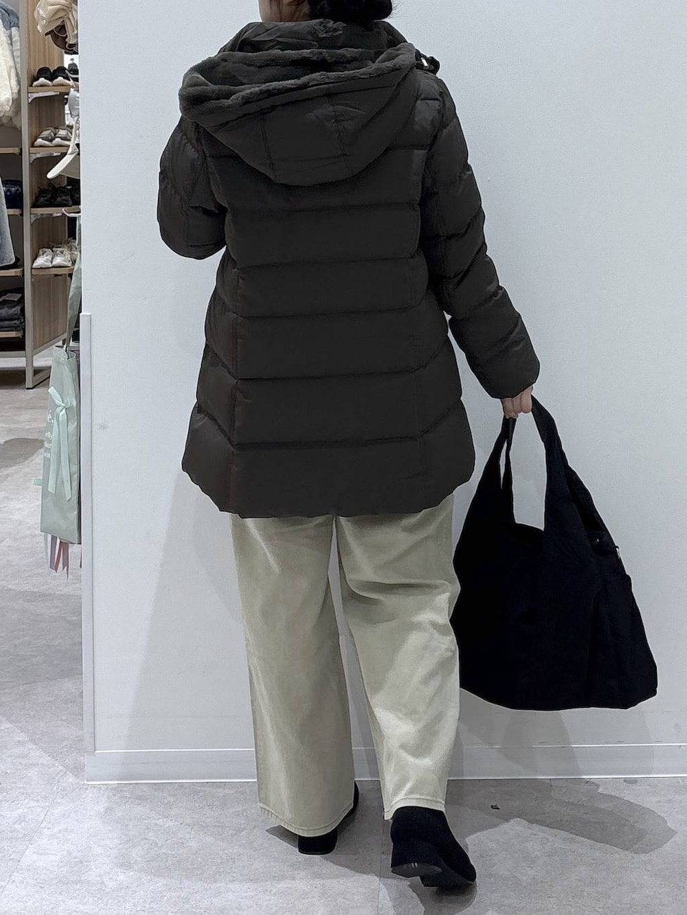 ブラック系のトートバッグ、ブラウン系のダウンジャケット/コート、ベージュ系のデニムパンツを着用したレディースの冬コーディネートの3枚目の写真