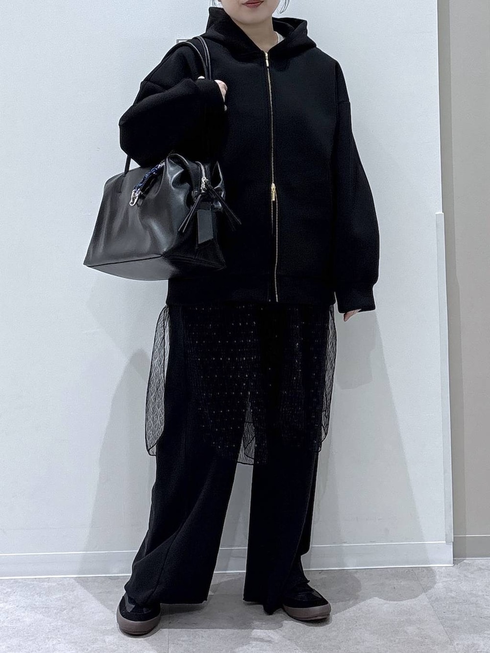 ブラック系のスニーカー、ブラック系のスウェットパンツ、ブラック系のパーカーを着用したレディースの冬コーディネートの4枚目の写真