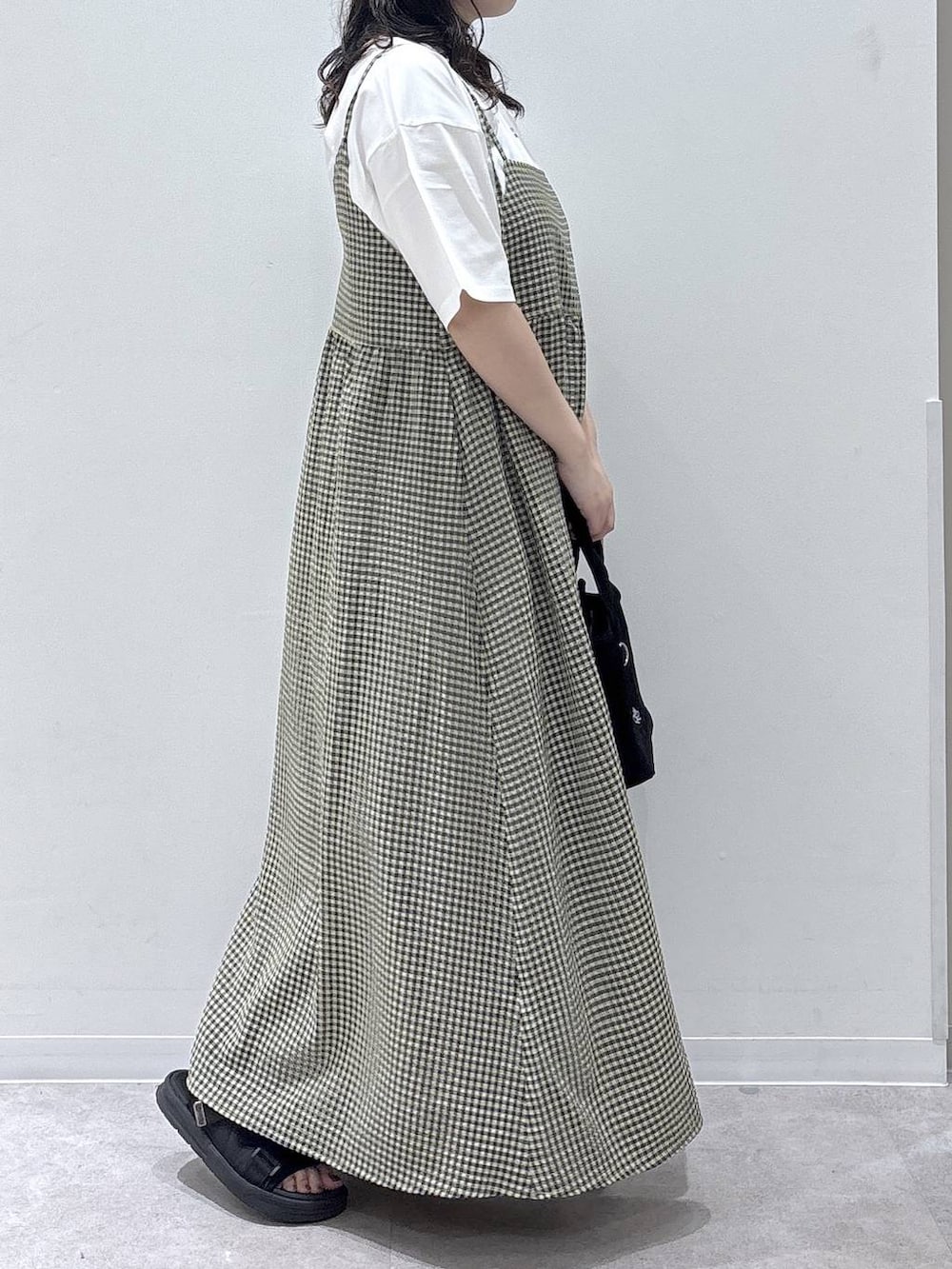 ブラック系のトートバッグ、ホワイト系のTシャツ/カットソー、ブラック系のサンダルを着用したレディースの夏コーディネートの2枚目の写真