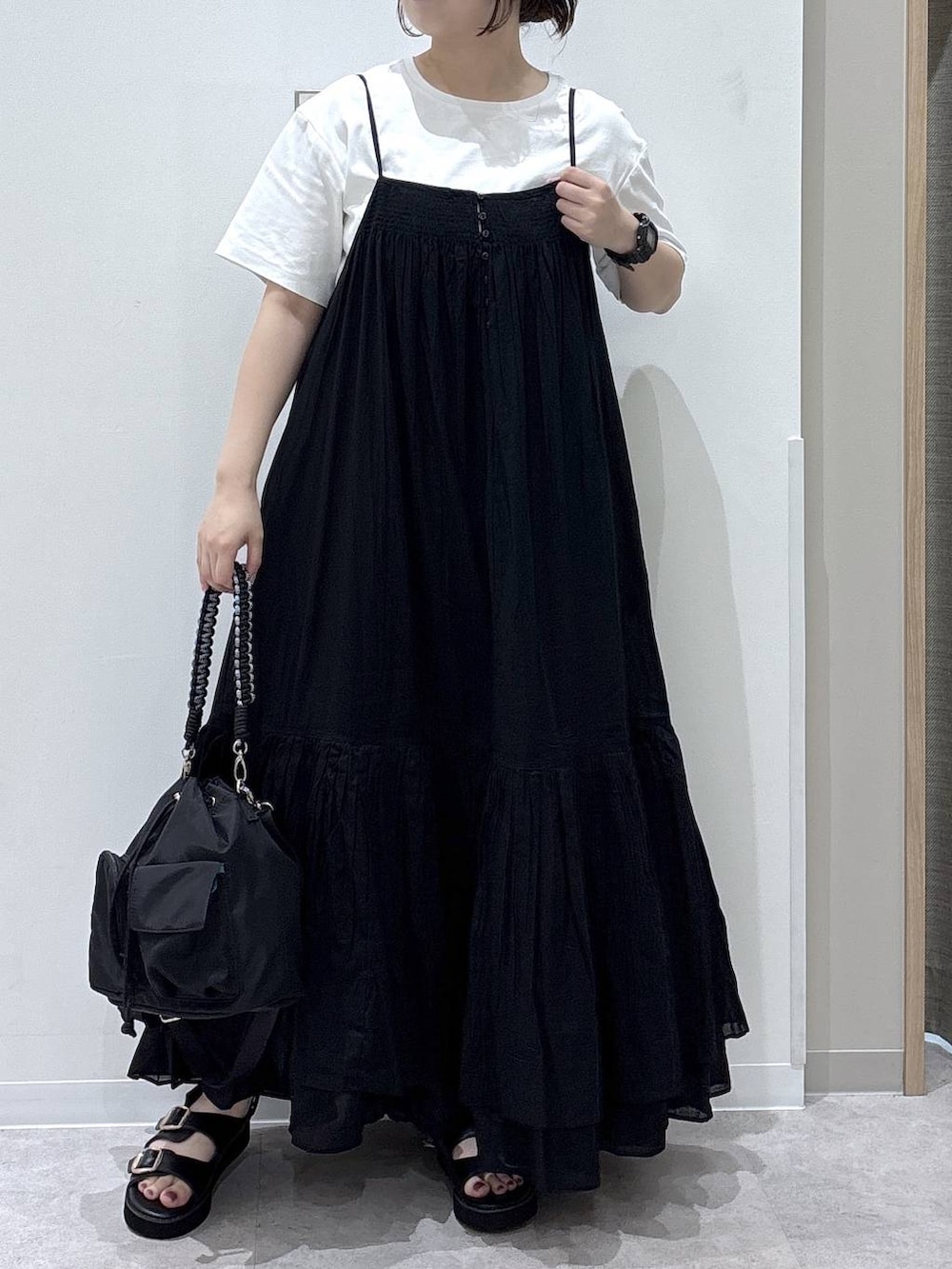 ブラック系のワンピース、ホワイト系のTシャツ/カットソー、ブラック系のサンダルを着用したレディースの夏コーディネートの4枚目の写真