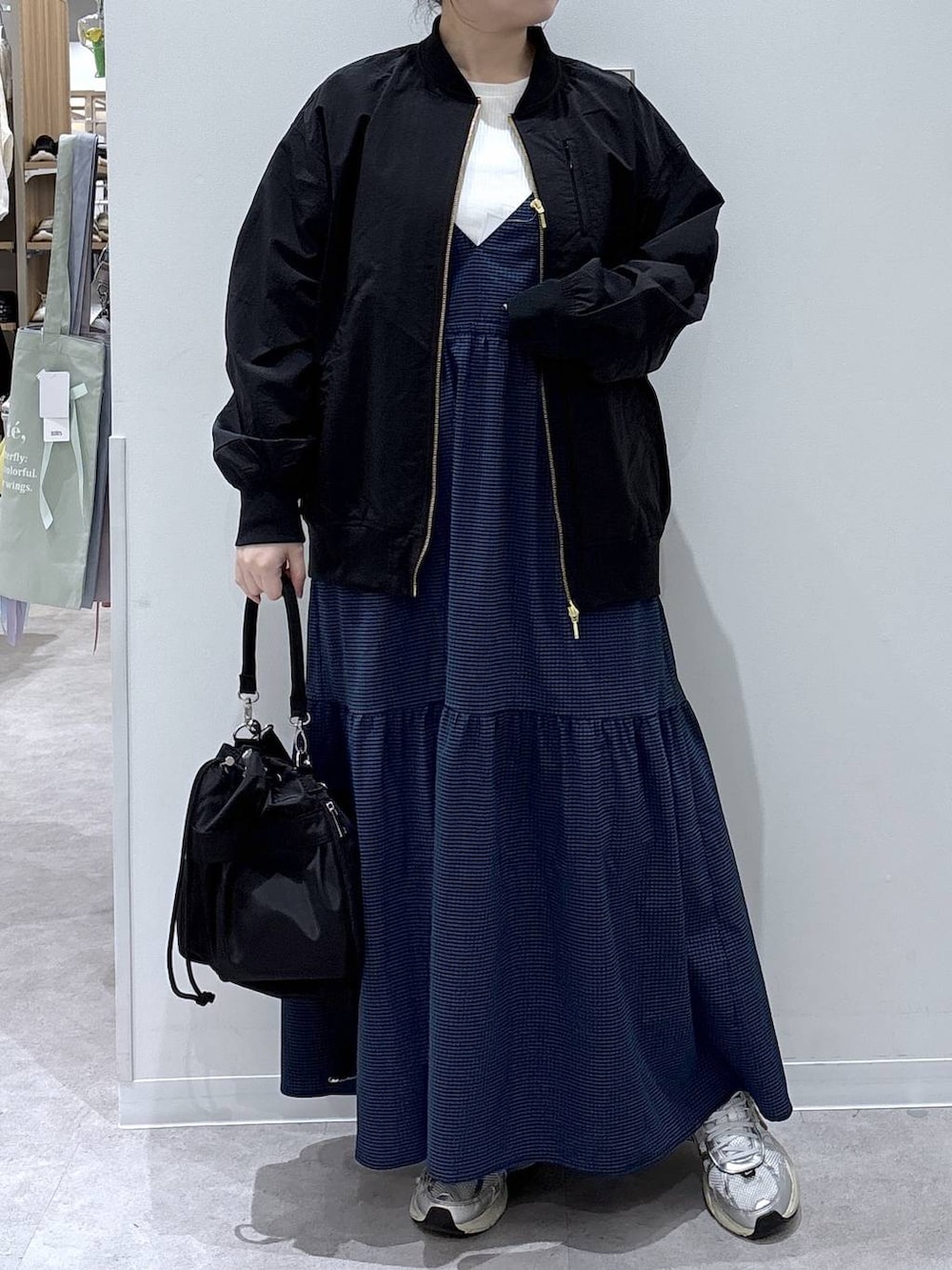 ブラック系のショルダーバッグ、ブラック系のブルゾン、ブルー系のワンピースを着用したレディースの春コーディネートの4枚目の写真