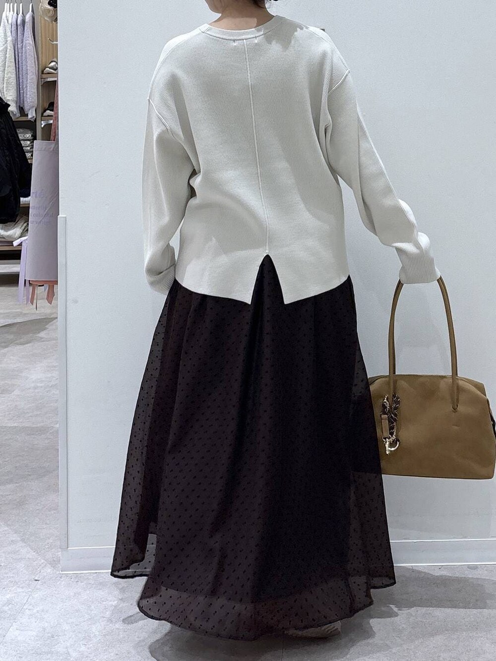 ベージュ系のボストンバッグ、ベージュ系のブーツ、ホワイト系のニット/セーターを着用したレディースの冬コーディネートの3枚目の写真