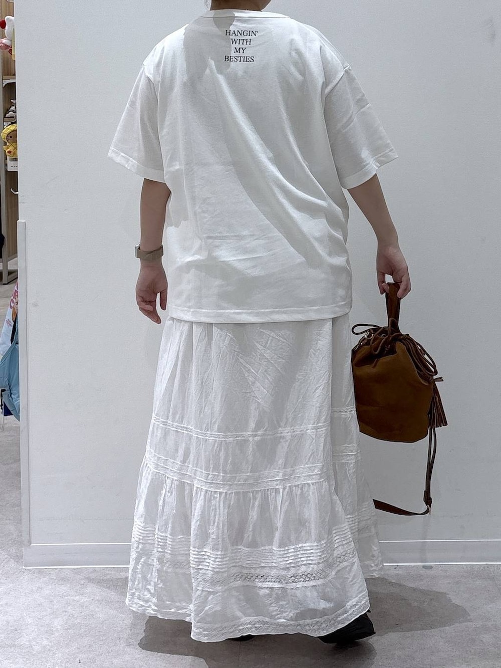 ベージュ系のハンドバッグ、ホワイト系のスカート、ホワイト系のTシャツ/カットソーを着用したレディースの夏コーディネートの3枚目の写真