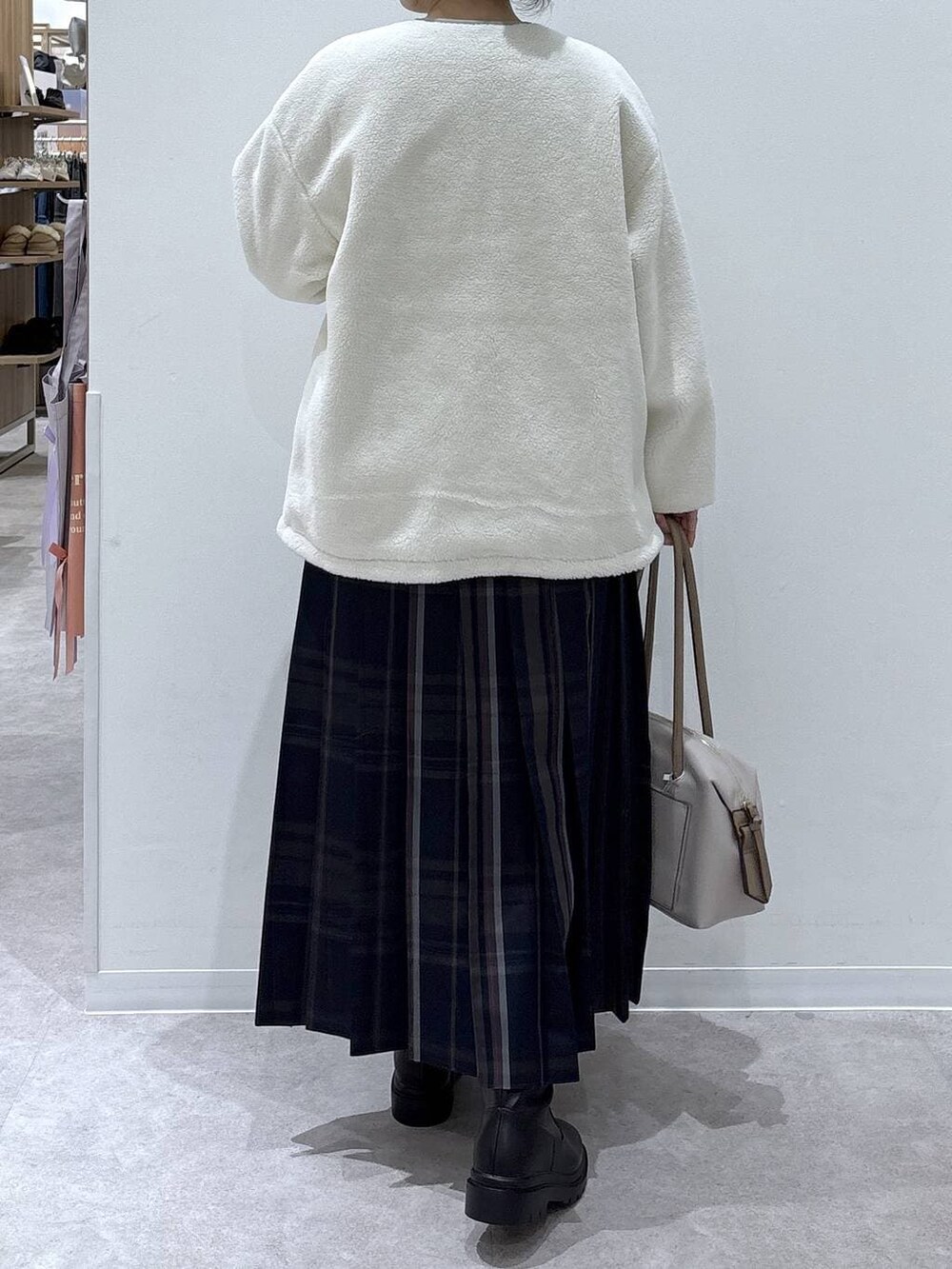 ホワイト系のボストンバッグ、ホワイト系のブルゾン、ブラック系のブーツを着用したレディースの冬コーディネートの3枚目の写真