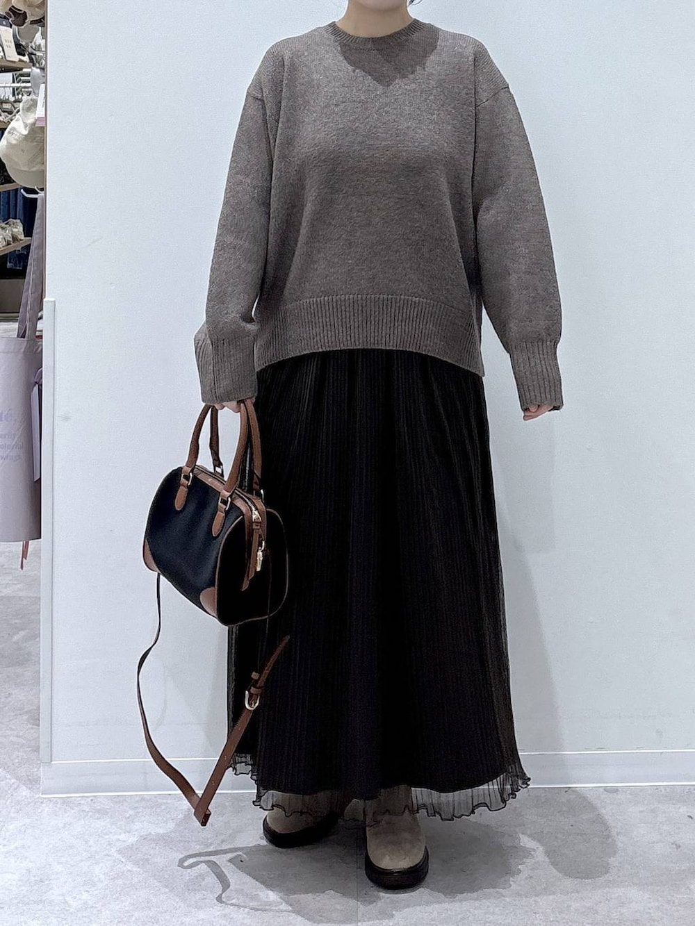 ブラウン系のダウンジャケット/コート、ベージュ系のブーツ、ブラック系のボストンバッグを着用したレディースの冬コーディネートの5枚目の写真