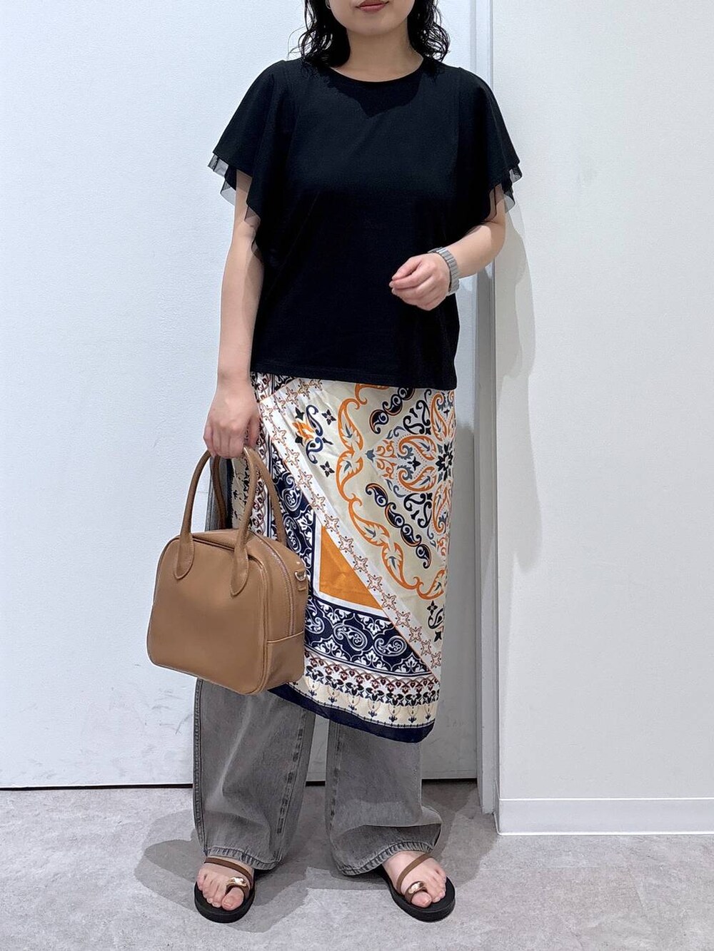 グレー系のデニムパンツ、ベージュ系のボストンバッグ、ブラック系のTシャツ/カットソーを着用したレディースの夏コーディネートの4枚目の写真