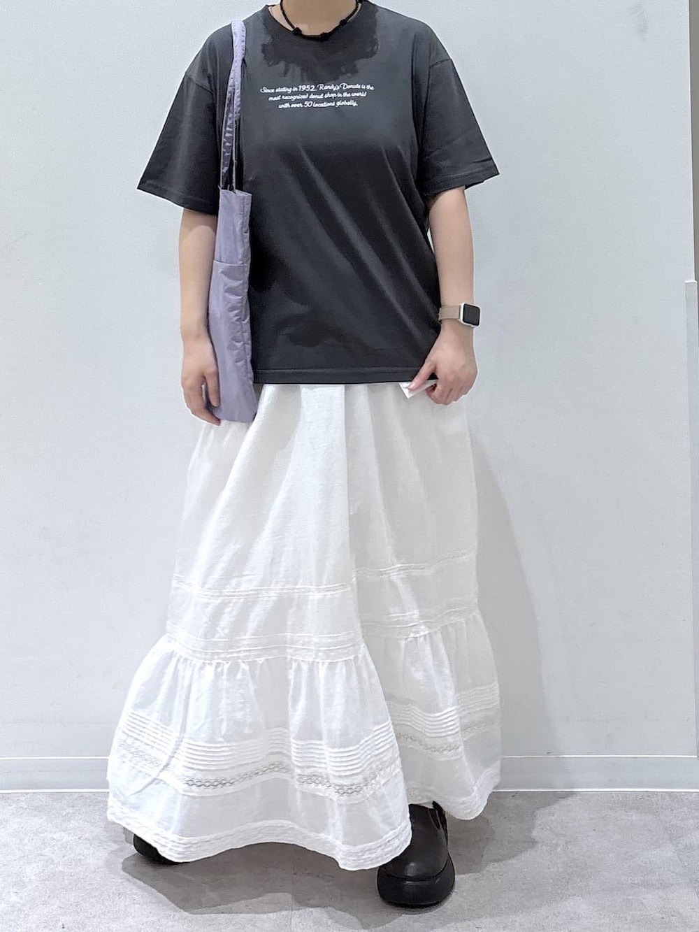 ホワイト系のスカート、パープル系のトートバッグ、グレー系のTシャツ/カットソーを着用したレディースの夏コーディネートの3枚目の写真
