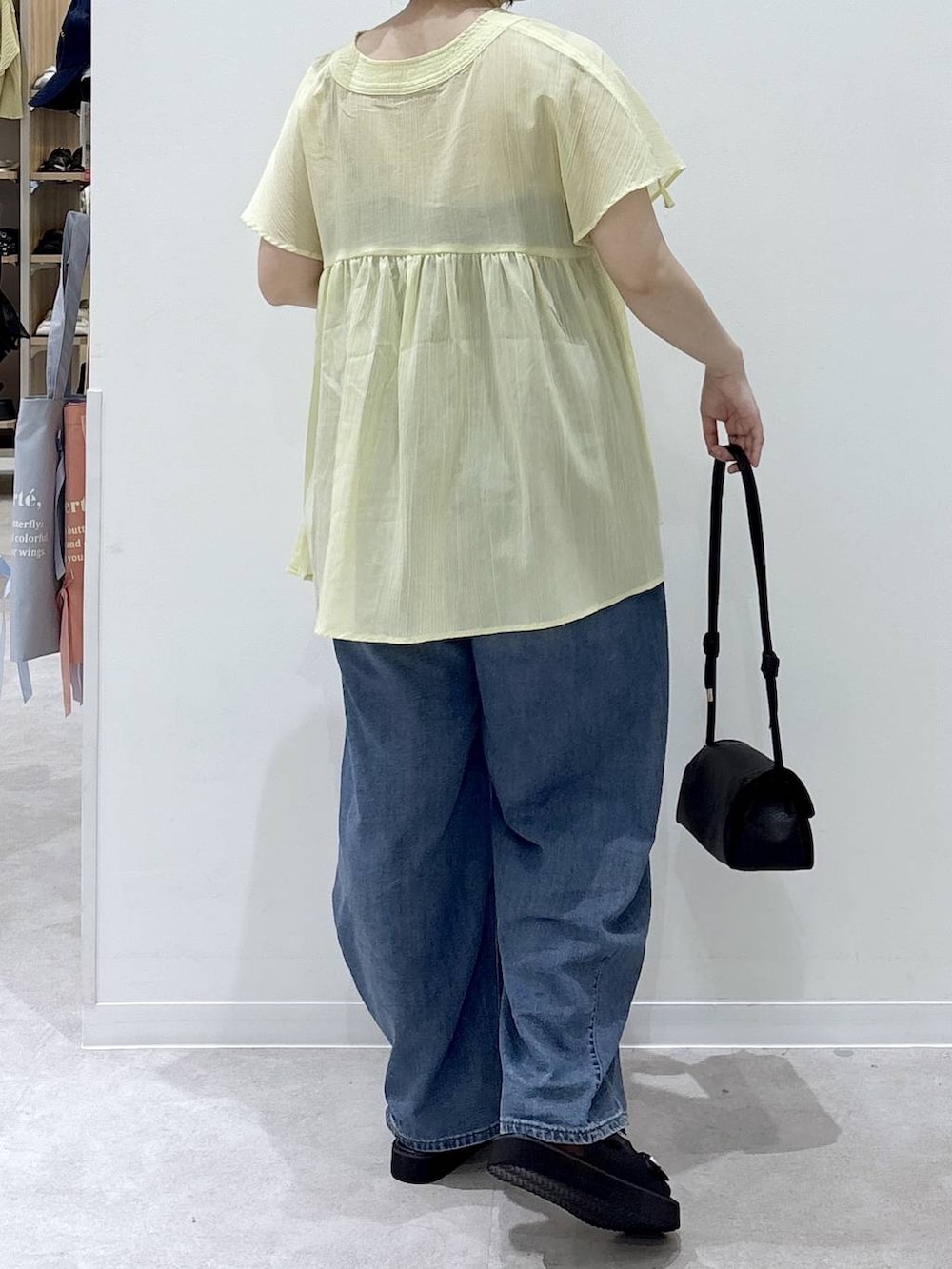 ブラック系のショルダーバッグ、ブルー系のデニムパンツ、イエロー系のシャツ/ブラウスを着用したレディースの夏コーディネートの3枚目の写真