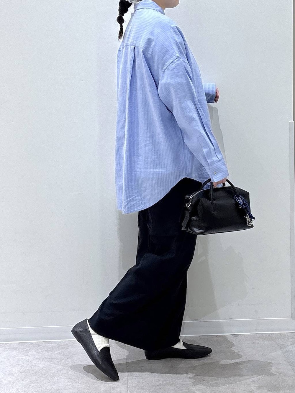 ブラック系のその他シューズ、ブラック系のボストンバッグ、ブルー系のシャツ/ブラウスを着用したレディースの春コーディネートの2枚目の写真