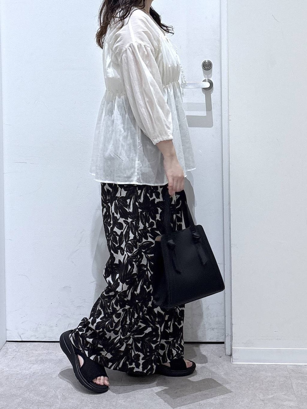 ブラック系のショルダーバッグ、ベージュ系のその他パンツ、ブラック系のサンダルを着用したレディースの春コーディネートの2枚目の写真