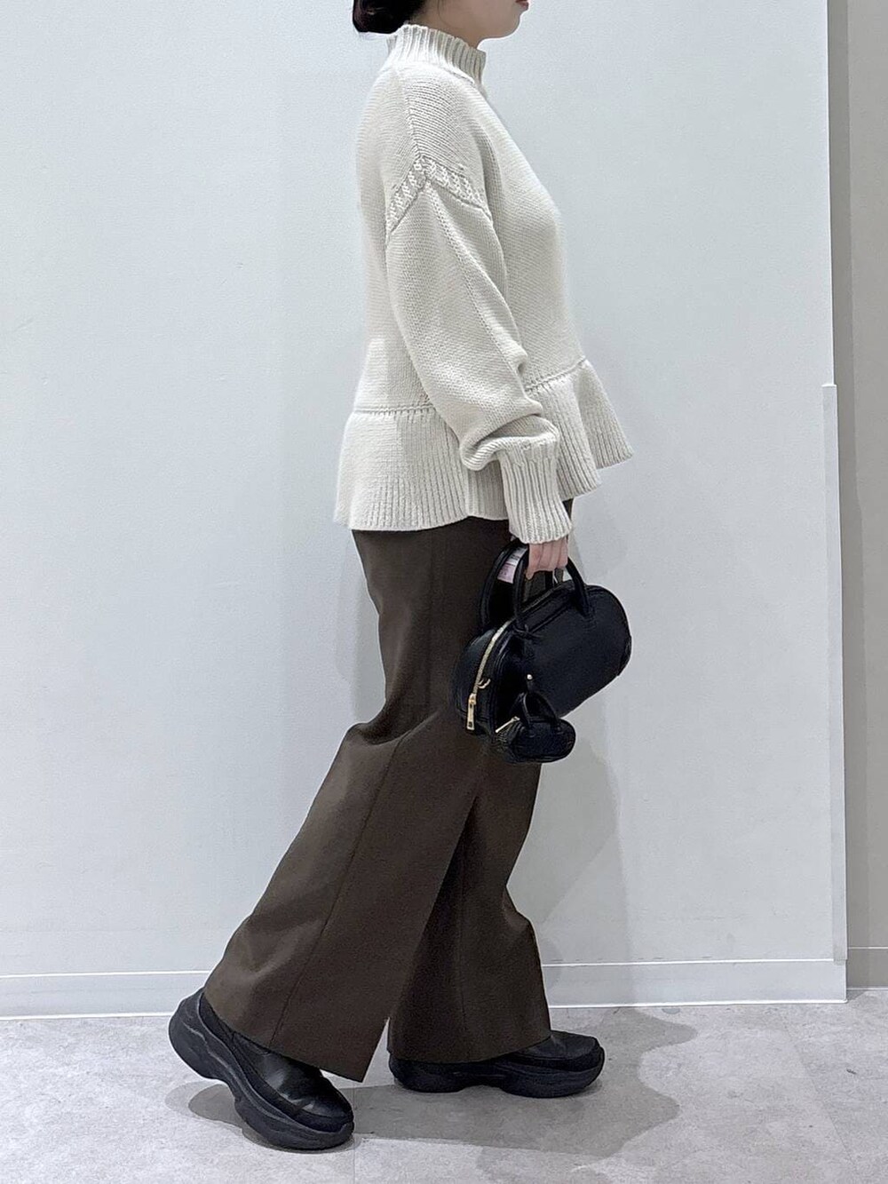 ブラウン系のその他パンツ、ブラック系のブーツ、ブラック系のハンドバッグを着用したレディースの冬コーディネートの2枚目の写真