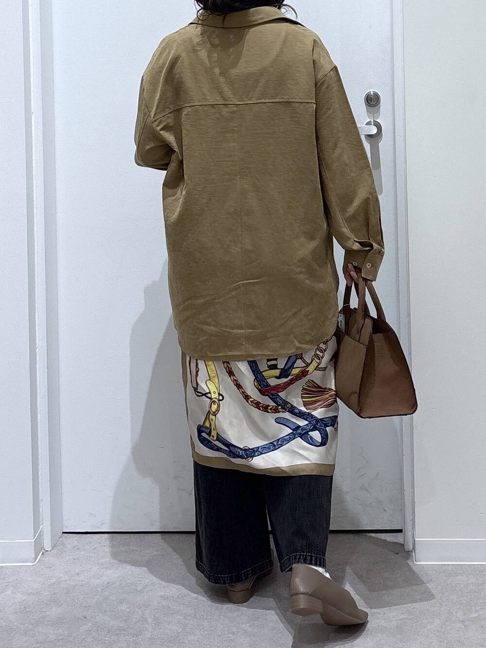 ブラック系のデニムパンツ、イエロー系のシャツ/ブラウス、ベージュ系のショルダーバッグを着用したレディースの秋コーディネートの3枚目の写真