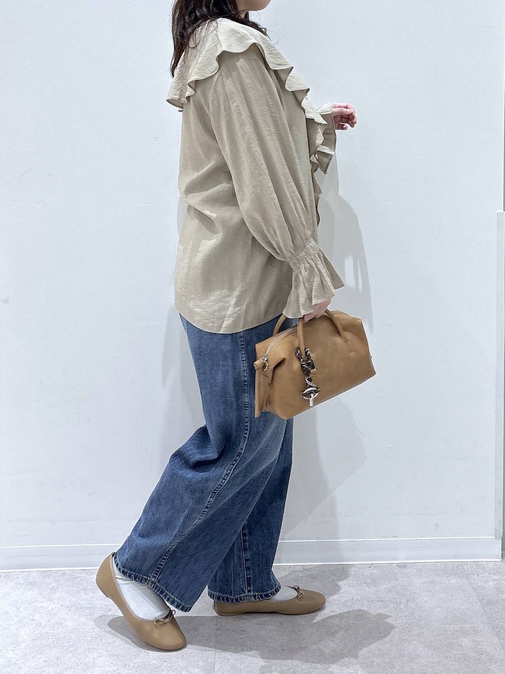 ブラウン系のバレエシューズ、ブルー系のデニムパンツ、ブラウン系のボストンバッグを着用したレディースの春コーディネートの2枚目の写真