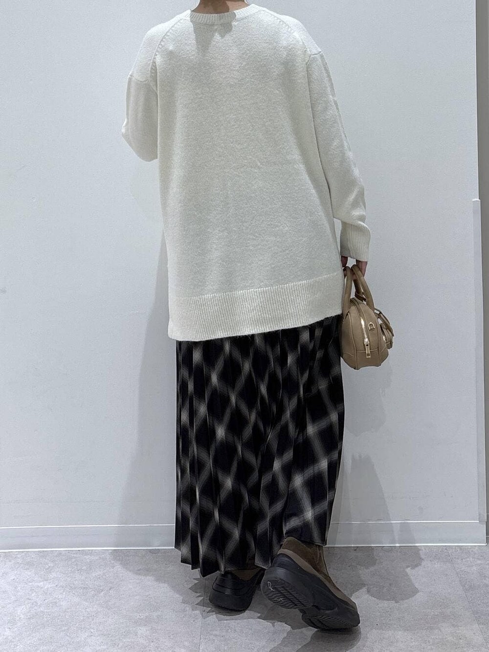 ホワイト系のカーディガン/ボレロ、ブラウン系のブーツ、ブラック系のスカートを着用したレディースの冬コーディネートの2枚目の写真