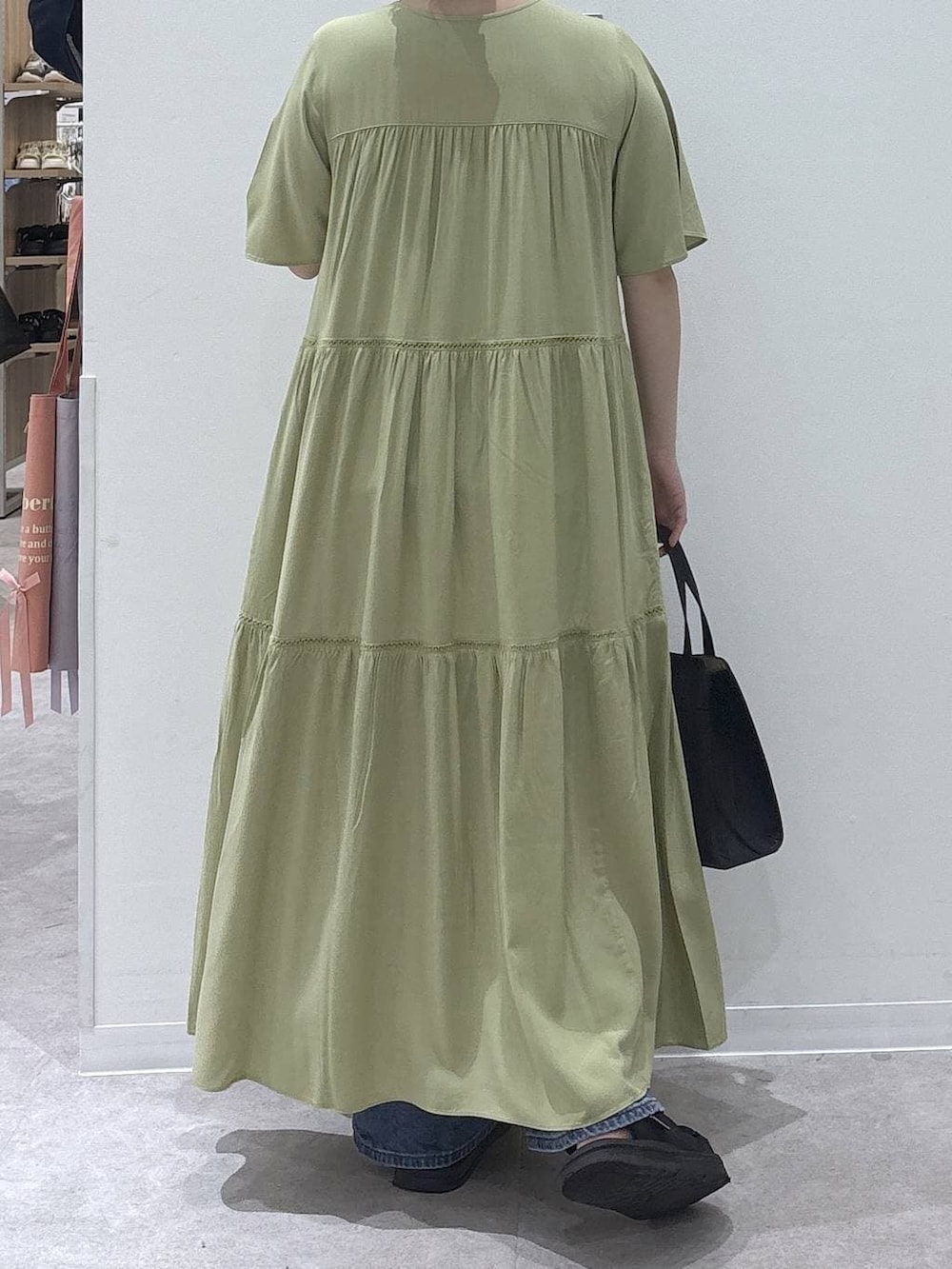 ブラック系のショルダーバッグ、ブルー系のデニムパンツ、ブラック系のサンダルを着用したレディースの夏コーディネートの3枚目の写真