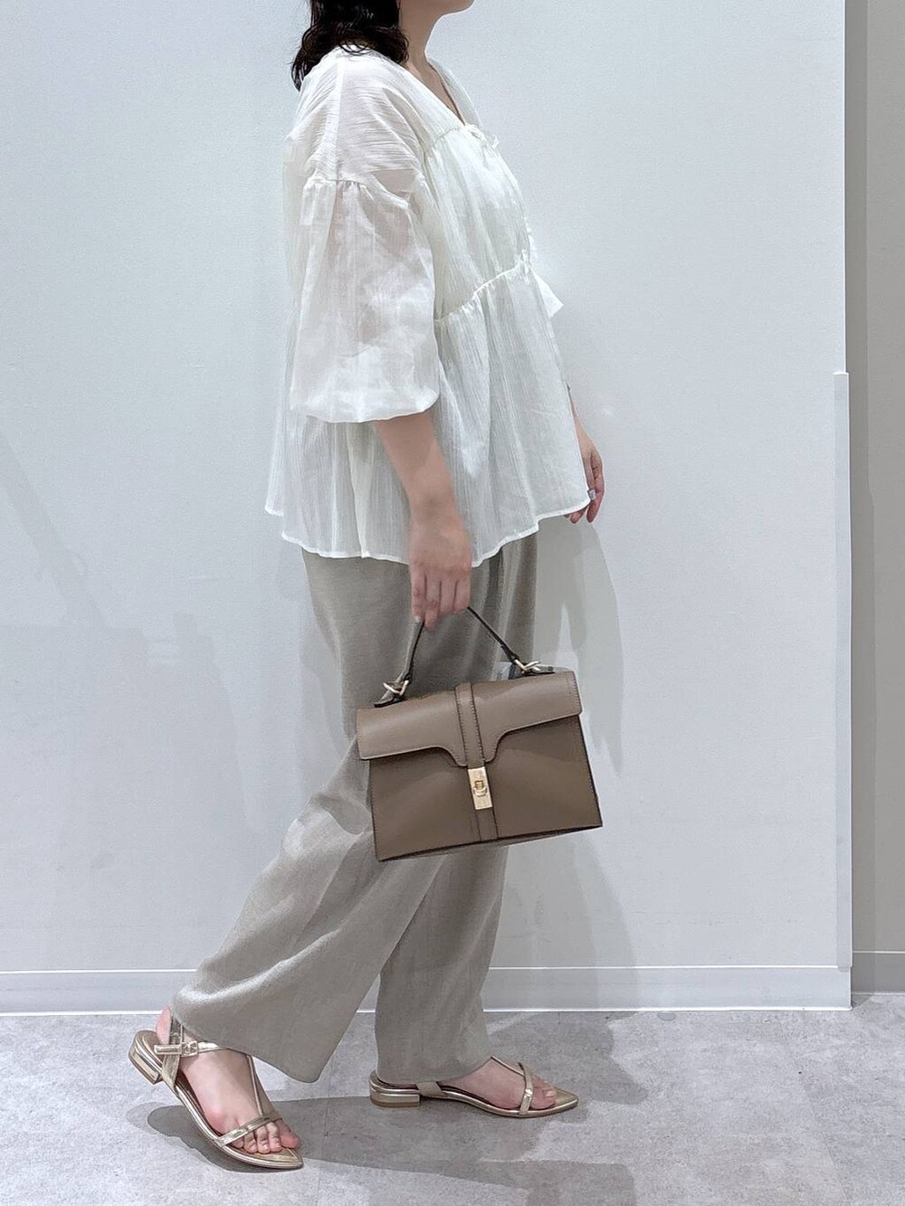 ベージュ系のショルダーバッグ、ベージュ系のその他パンツ、ゴールド系のサンダルを着用したレディースの夏コーディネートの2枚目の写真