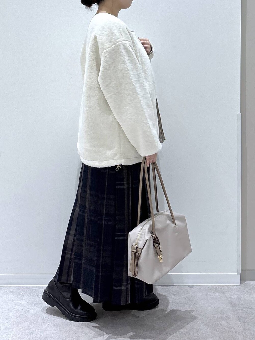 ホワイト系のボストンバッグ、ホワイト系のブルゾン、ブラック系のブーツを着用したレディースの冬コーディネートの2枚目の写真