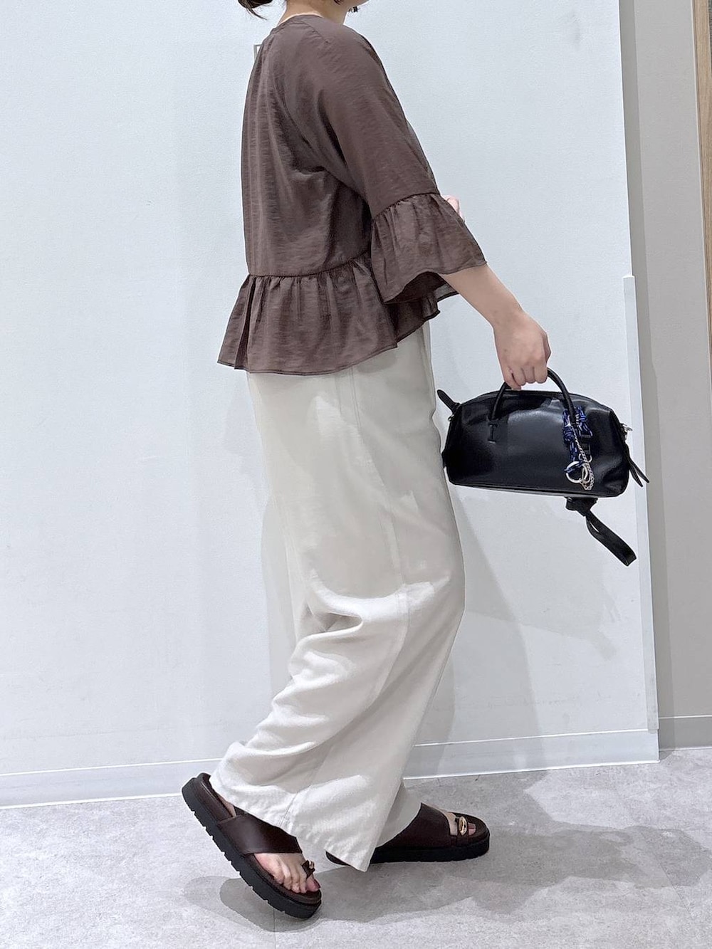 ベージュ系のその他パンツ、ブラック系のボストンバッグ、ブラウン系のカーディガン/ボレロを着用したレディースの夏コーディネートの2枚目の写真
