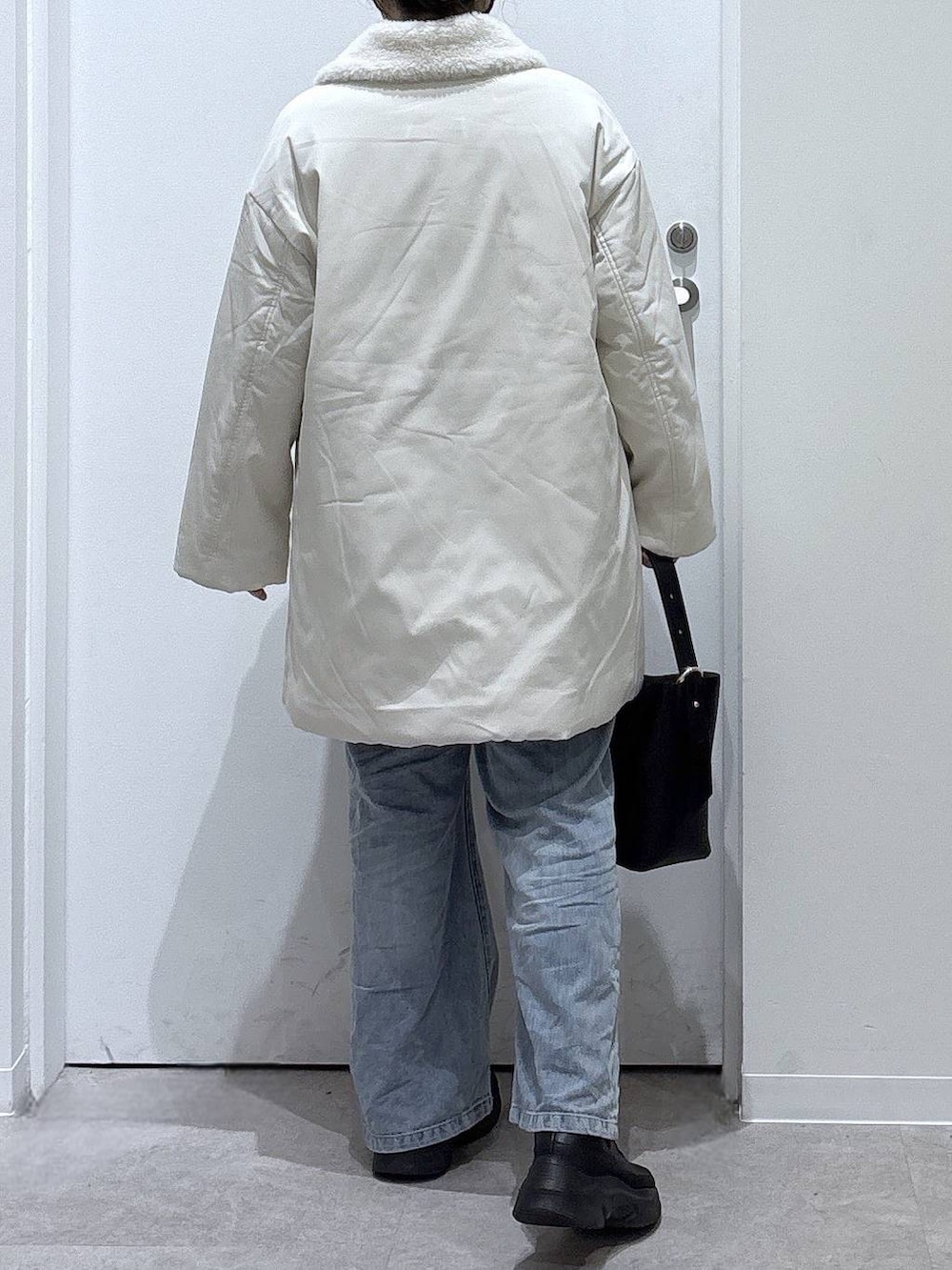 ブラック系のショルダーバッグ、ブルー系のデニムパンツ、ブラック系のブーツを着用したレディースの秋コーディネートの3枚目の写真