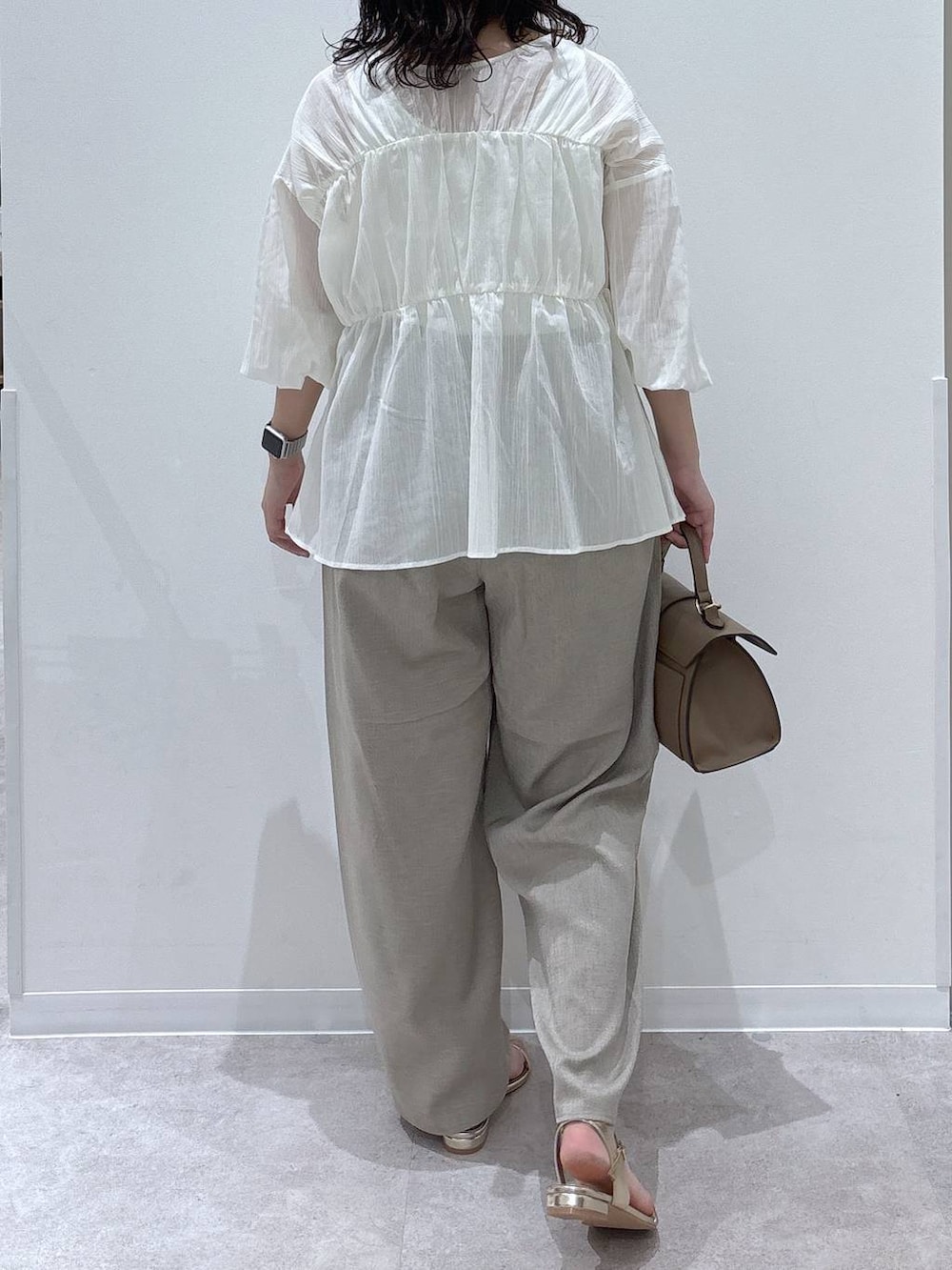 ベージュ系のショルダーバッグ、ベージュ系のその他パンツ、ゴールド系のサンダルを着用したレディースの夏コーディネートの3枚目の写真