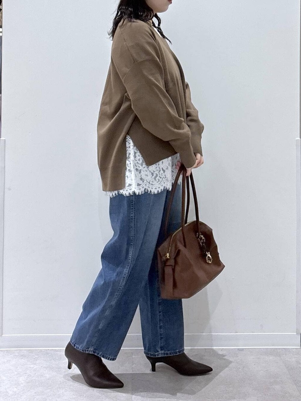 ブラウン系のボストンバッグ、ホワイト系のTシャツ/カットソー、ブラウン系のブーツを着用したレディースの冬コーディネートの2枚目の写真