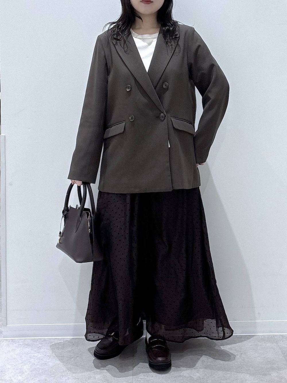 ブラウン系のショルダーバッグ、ブラウン系のテーラードジャケット、ブラウン系のスカートを着用したレディースの冬コーディネートの4枚目の写真