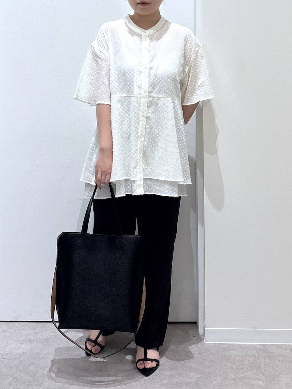 ブラック系のトートバッグ、ブラウン系のスラックス、ブラック系のサンダルを着用したレディースの夏コーディネートの5枚目の写真