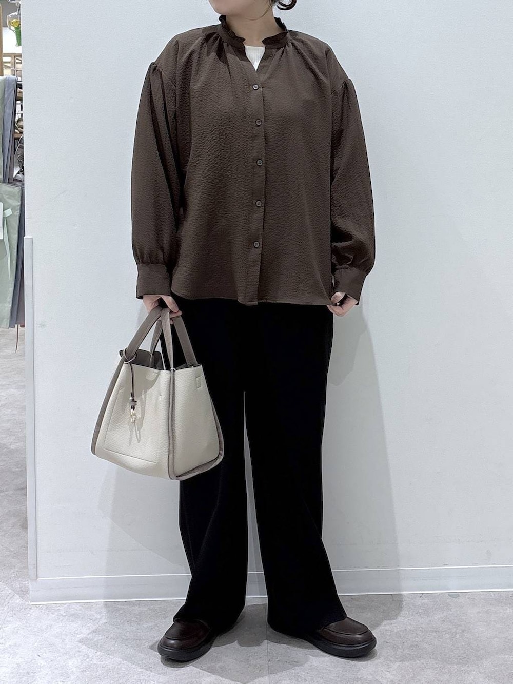 ベージュ系のトートバッグ、ブラック系のスラックス、ブラウン系のシャツ/ブラウスを着用したレディースの春コーディネートの4枚目の写真