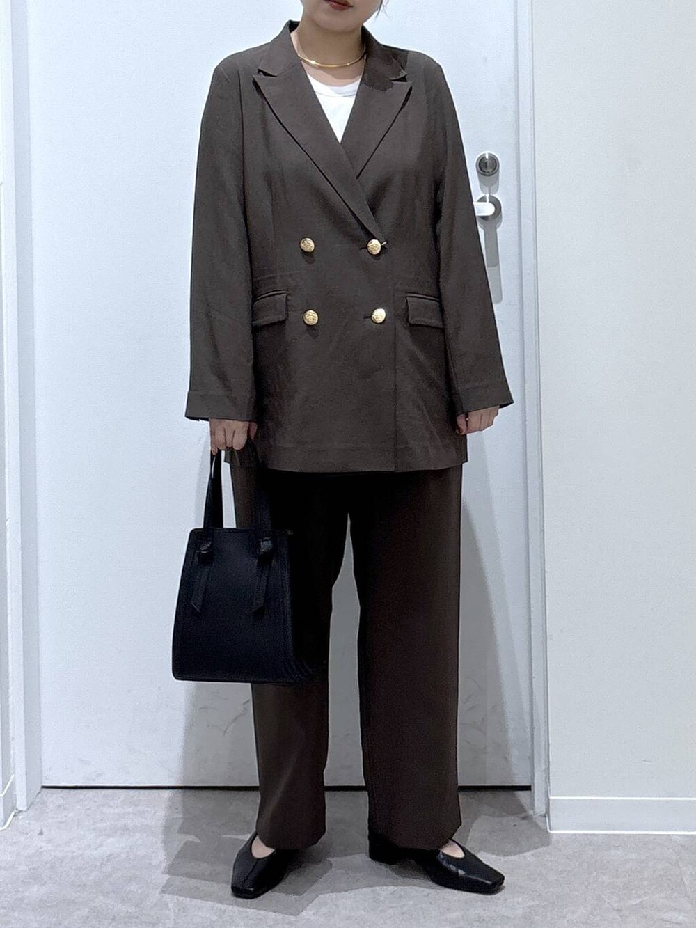 ブラック系のショルダーバッグ、ブラウン系のテーラードジャケット、ブラウン系のスラックスを着用したレディースの秋コーディネートの5枚目の写真