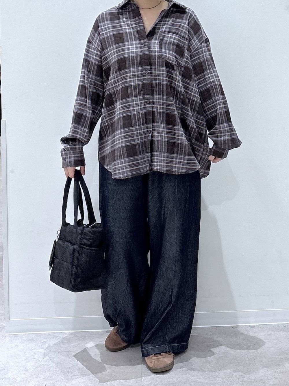 ブラック系のトートバッグ、ブラウン系のシャツ/ブラウス、ブルー系のデニムパンツを着用したレディースの秋コーディネートの4枚目の写真