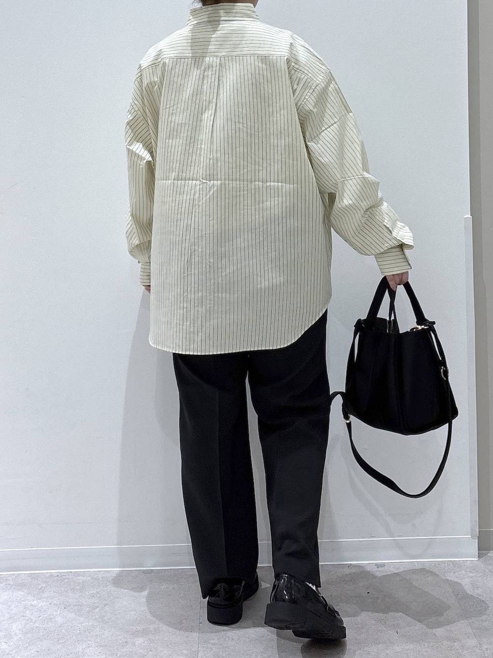 ブラック系のトートバッグ、ブラック系のスラックス、イエロー系のシャツ/ブラウスを着用したレディースの春コーディネートの3枚目の写真