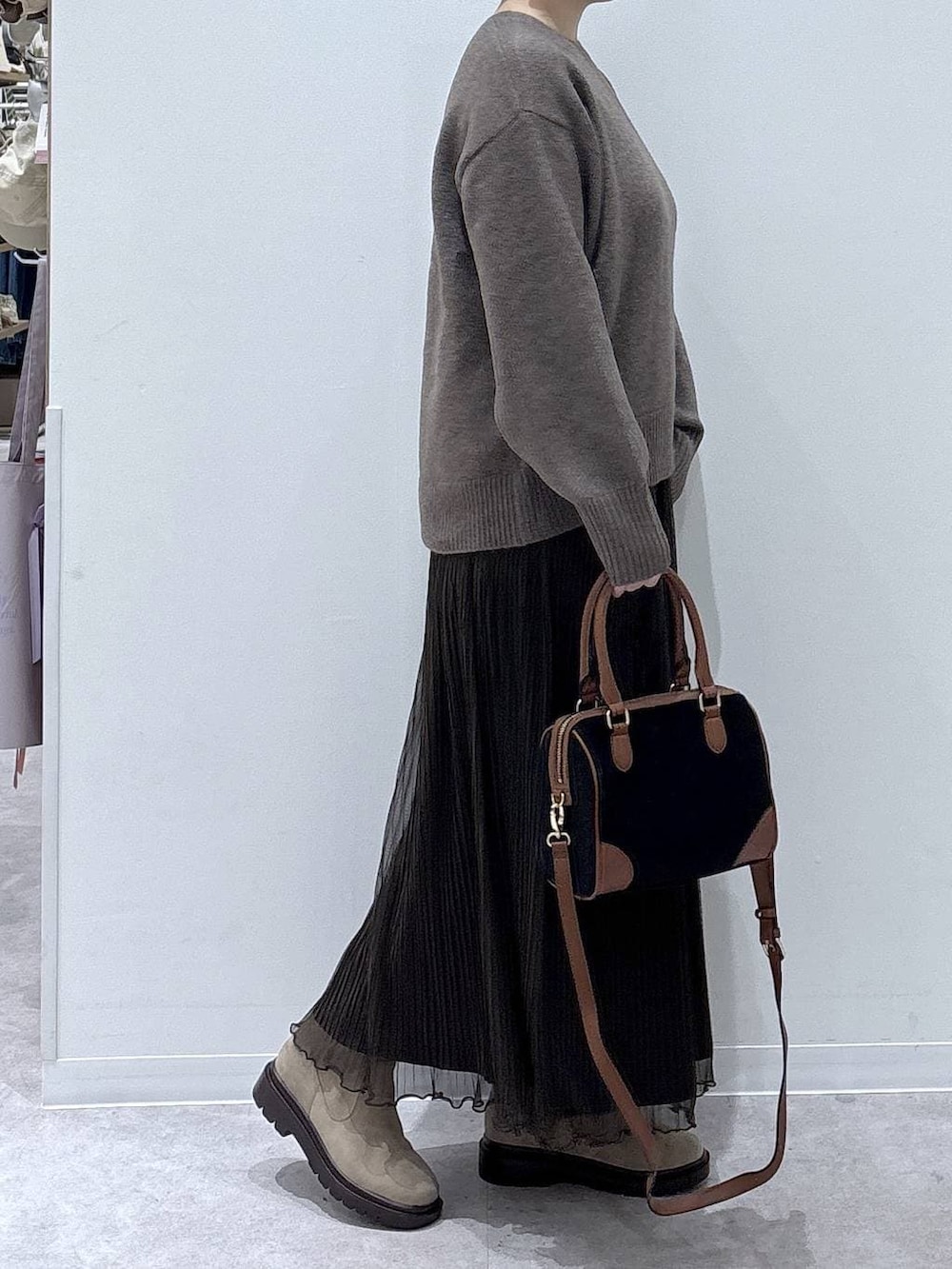 ブラウン系のダウンジャケット/コート、ベージュ系のブーツ、ブラック系のボストンバッグを着用したレディースの冬コーディネートの6枚目の写真