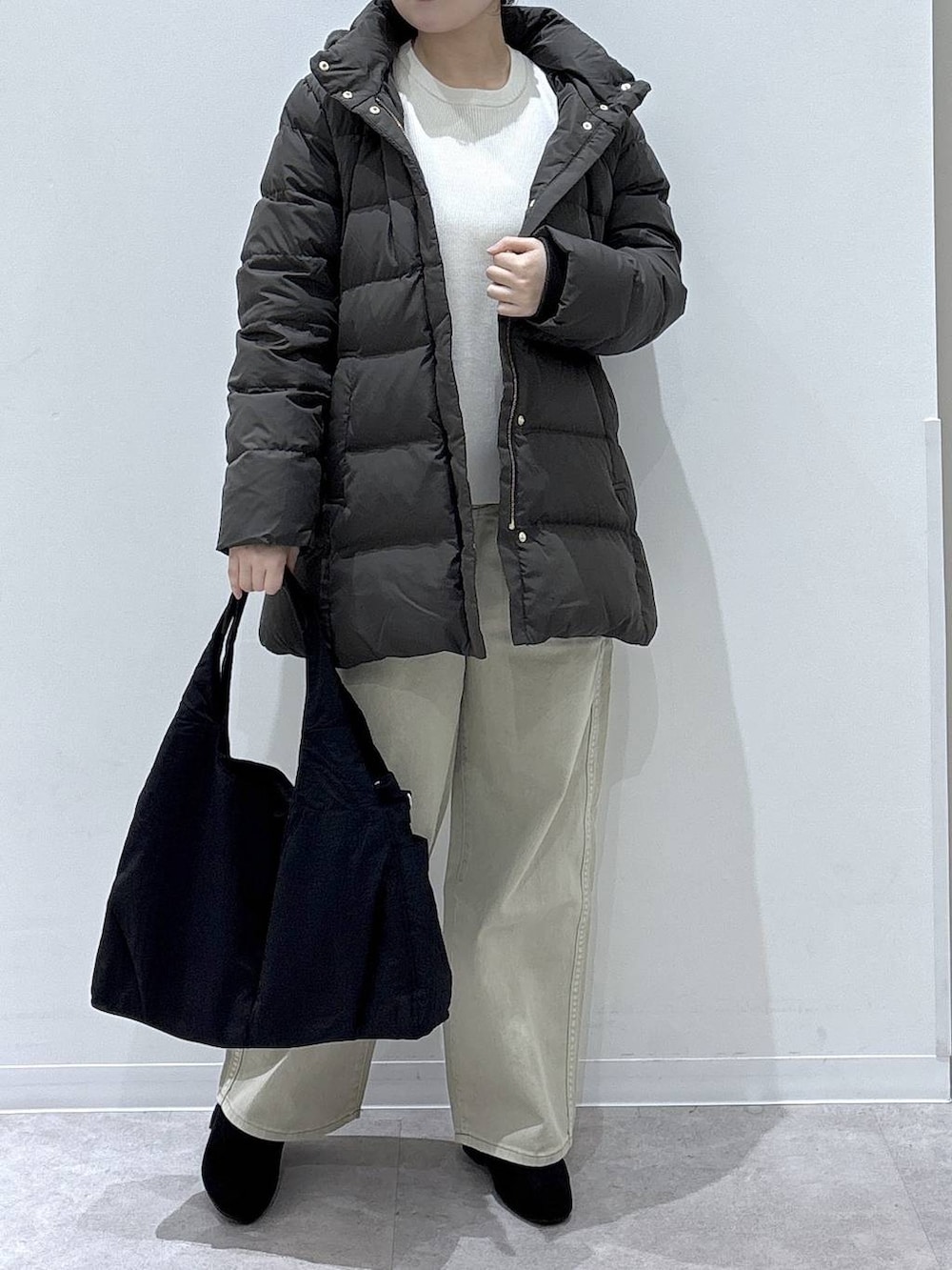 ブラック系のトートバッグ、ブラウン系のダウンジャケット/コート、ベージュ系のデニムパンツを着用したレディースの冬コーディネートの4枚目の写真