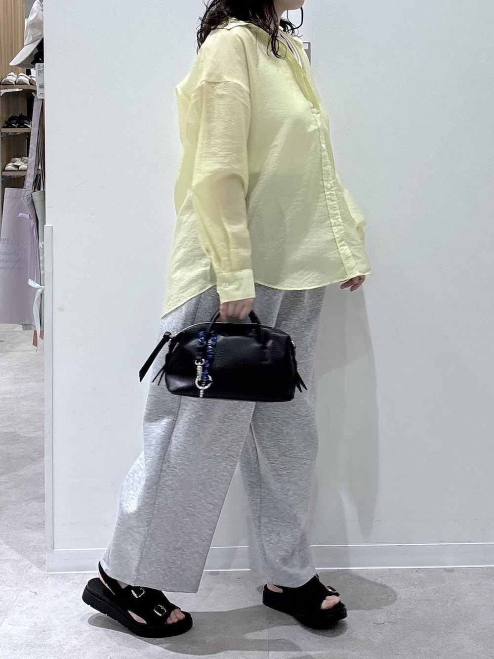 イエロー系のシャツ/ブラウス、ブラック系のボストンバッグ、ブラック系のサンダルを着用したレディースの春コーディネートの2枚目の写真