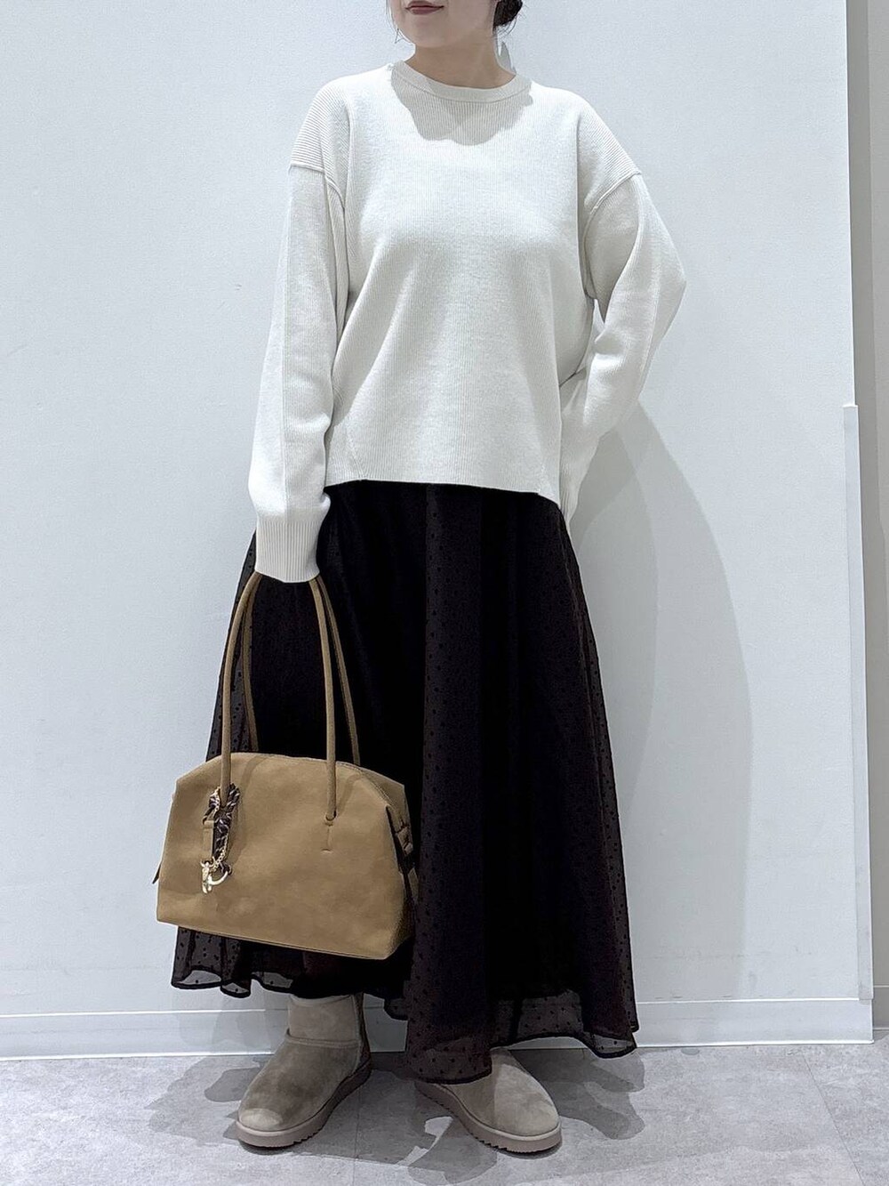 ベージュ系のボストンバッグ、ベージュ系のブーツ、ホワイト系のニット/セーターを着用したレディースの冬コーディネートの4枚目の写真
