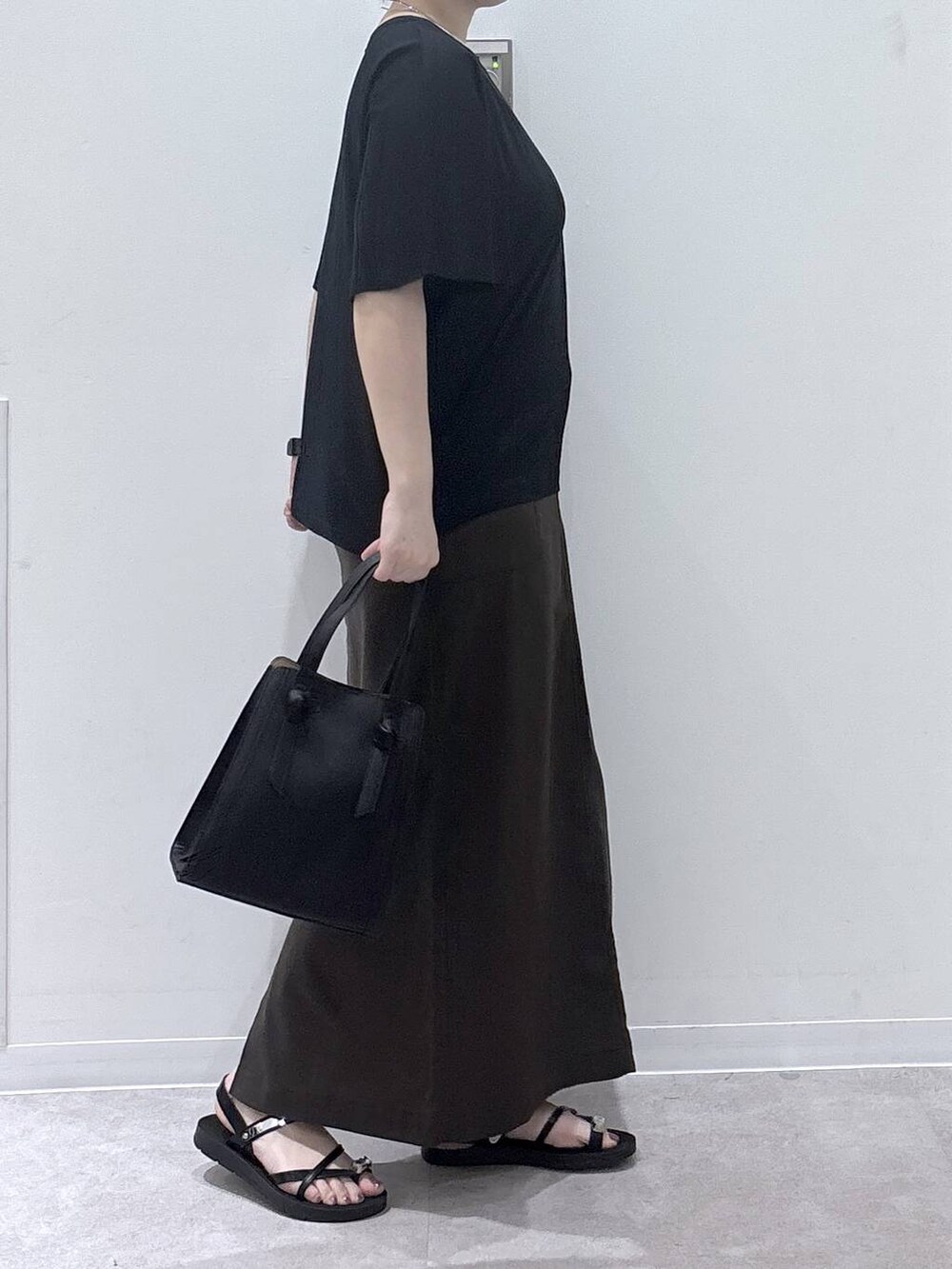 ブラック系のショルダーバッグ、ブラウン系のスカート、ブラック系のTシャツ/カットソーを着用したレディースの夏コーディネートの2枚目の写真