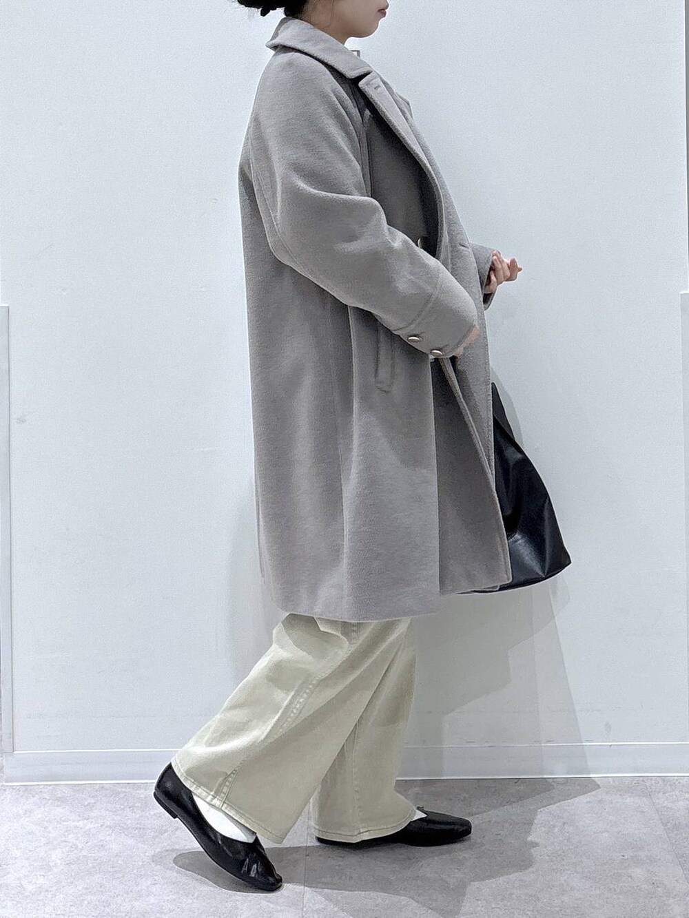 ブラック系のパンプス、ベージュ系のデニムパンツ、ベージュ系のチェスターコートを着用したレディースの冬コーディネートの2枚目の写真