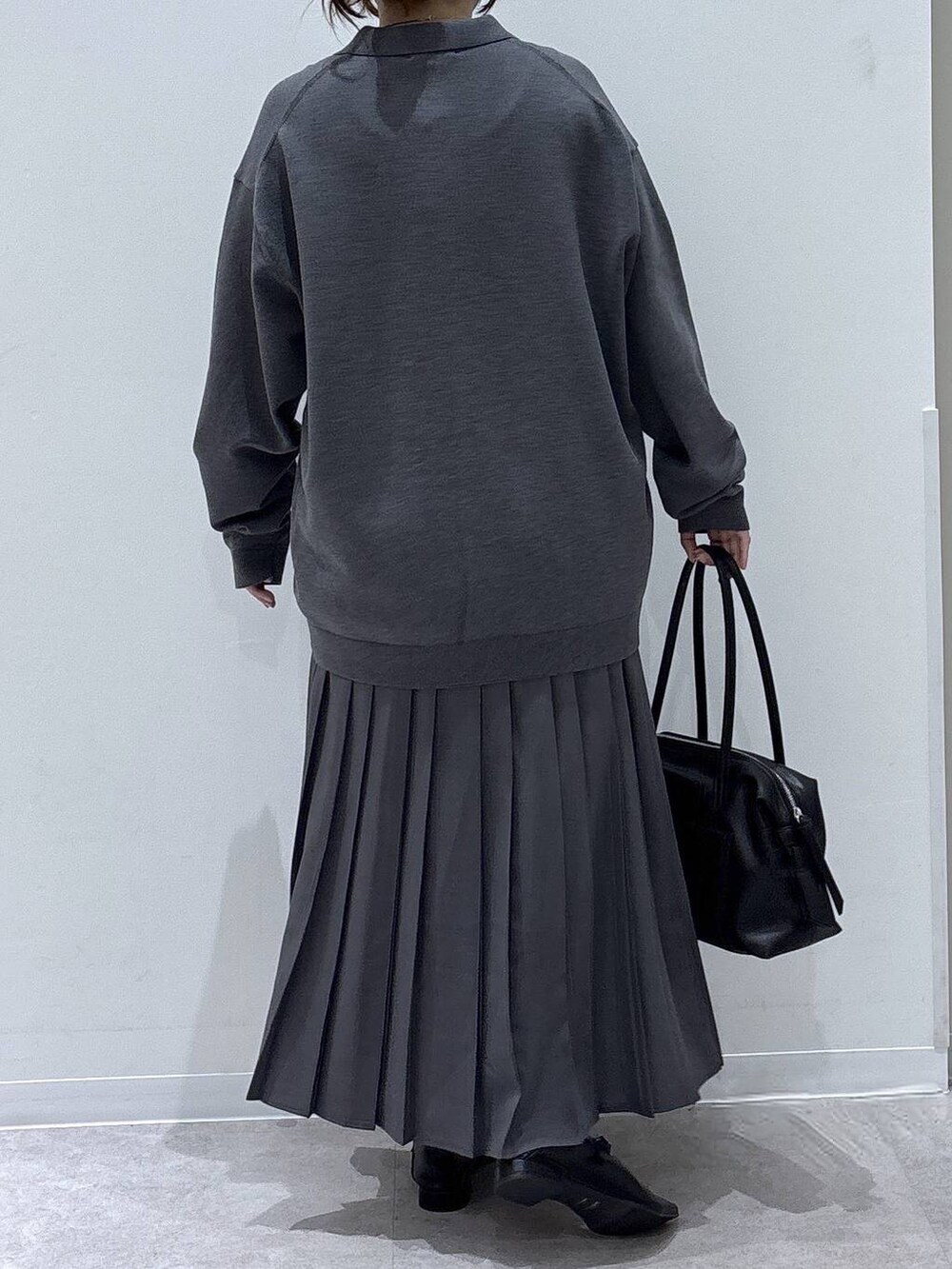 ブラック系のパンプス、ブラック系のボストンバッグ、グレー系のスカートを着用したレディースの秋コーディネートの3枚目の写真