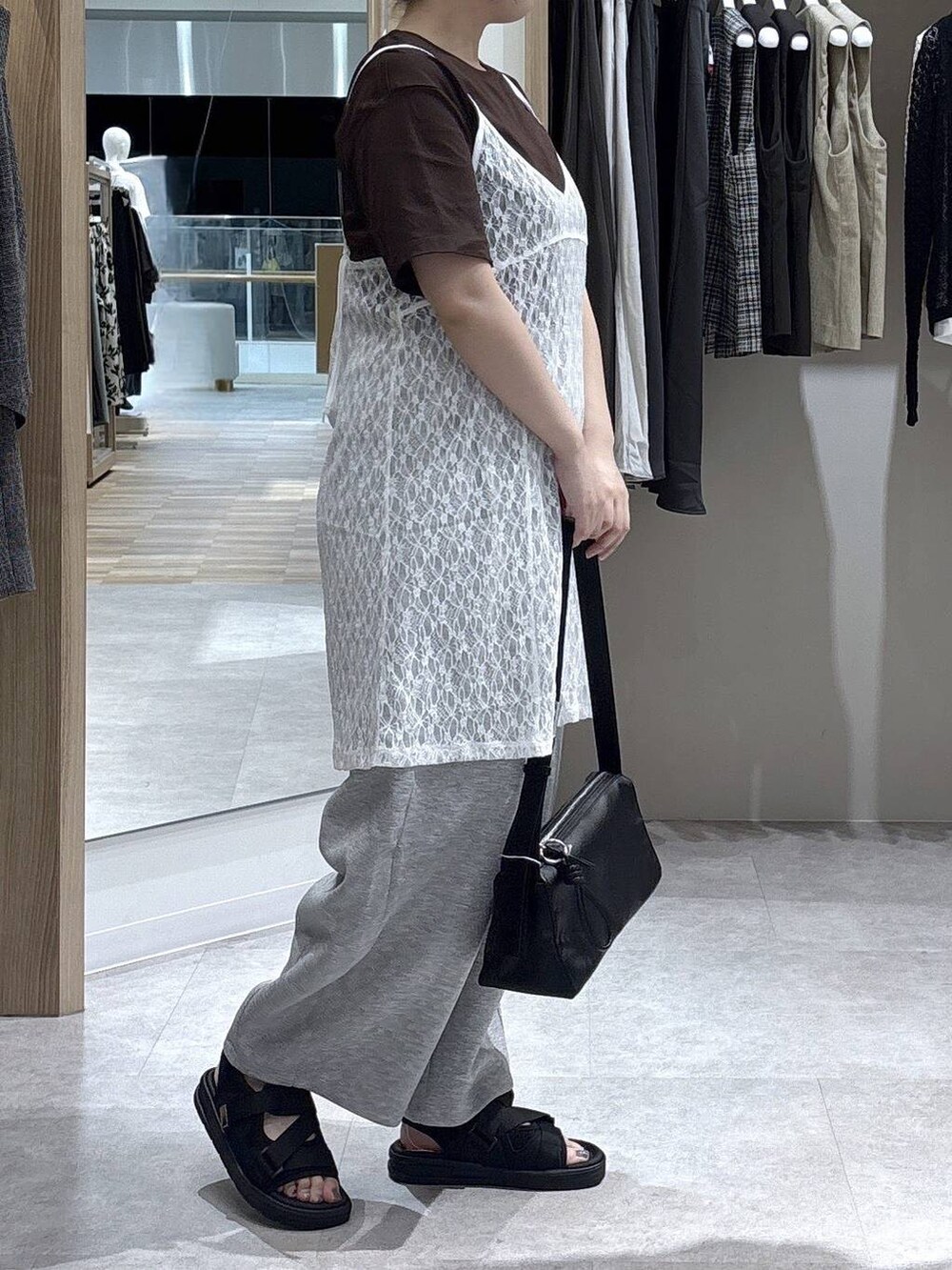 ブラウン系のショルダーバッグ、ブラウン系のTシャツ/カットソー、ブラック系のサンダルを着用したレディースの夏コーディネートの2枚目の写真