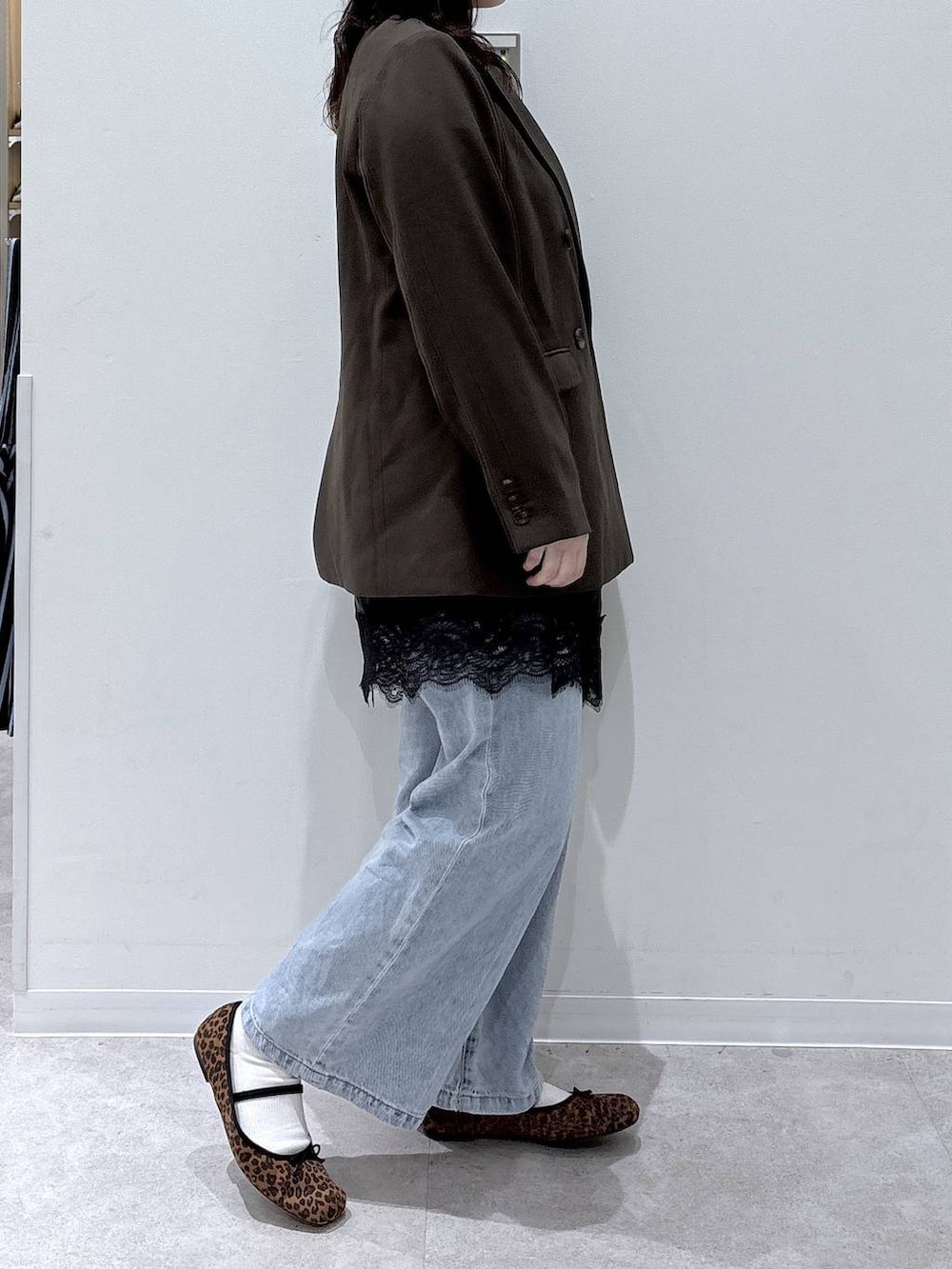 ブルー系のデニムパンツ、ブラウン系のテーラードジャケット、ゴールド系のネックレスを着用したレディースの春コーディネートの2枚目の写真