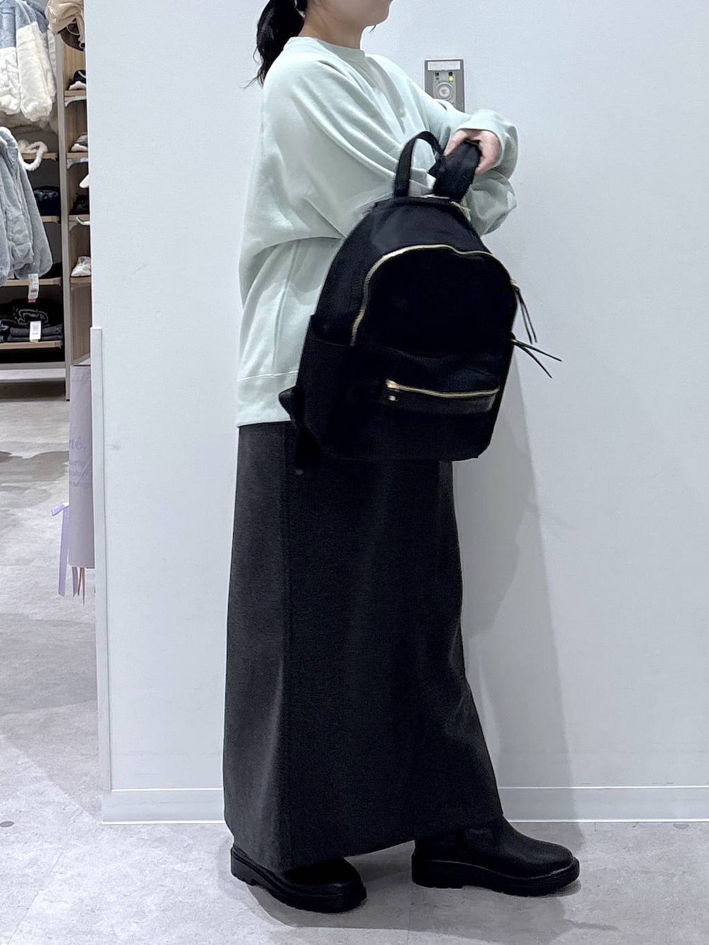 ブラック系のバックパック/リュック、ブラック系のブーツ、グレー系のスカートを着用したレディースの冬コーディネートの2枚目の写真