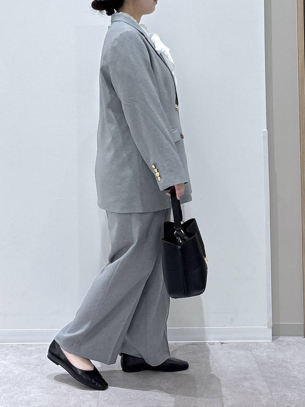 ブラック系のパンプス、ブラック系のショルダーバッグ、グレー系のテーラードジャケットを着用したレディースの冬コーディネートの2枚目の写真