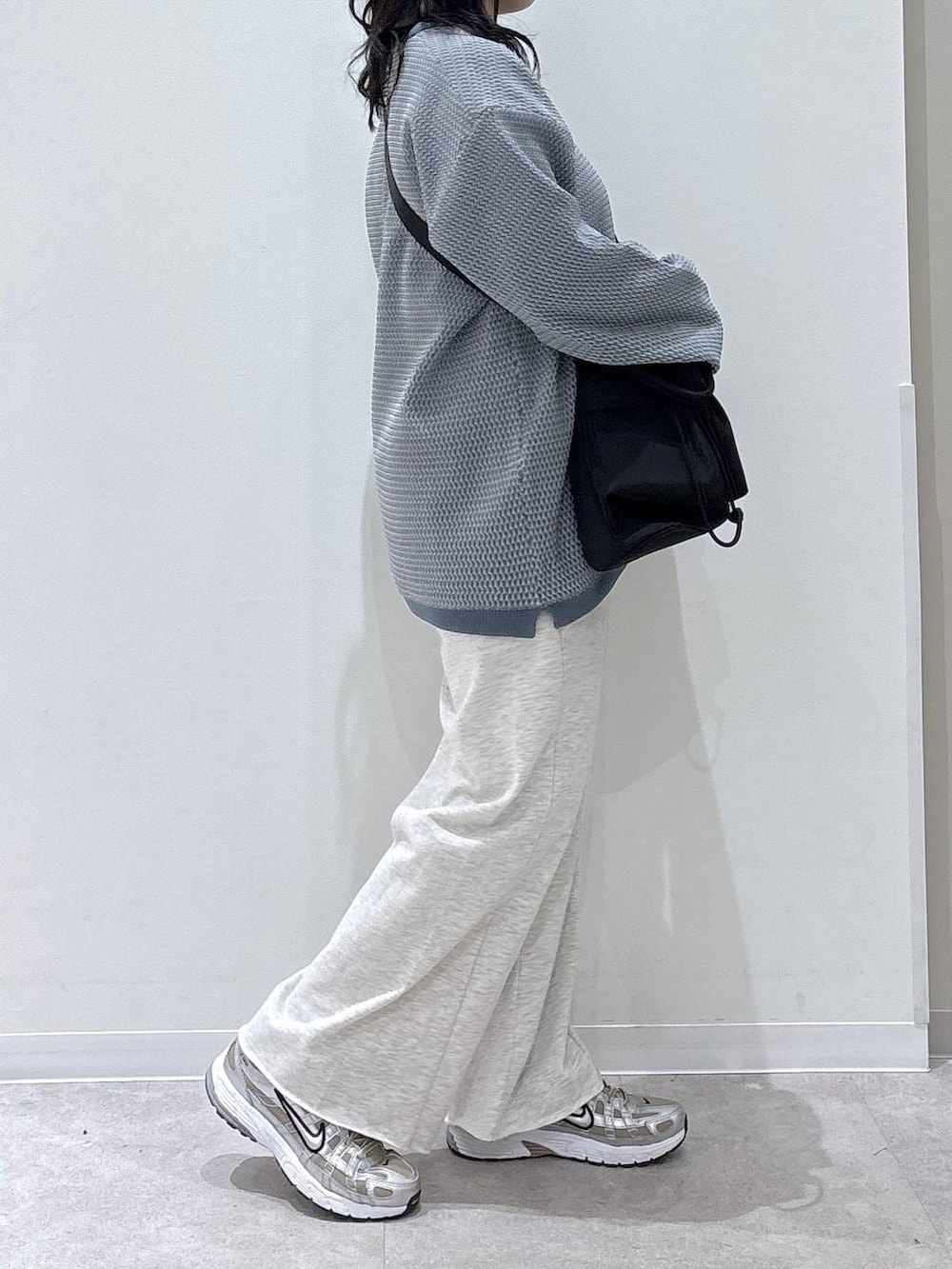 ブラック系のショルダーバッグ、ホワイト系のスウェットパンツ、ブルー系のニット/セーターを着用したレディースの冬コーディネートの2枚目の写真