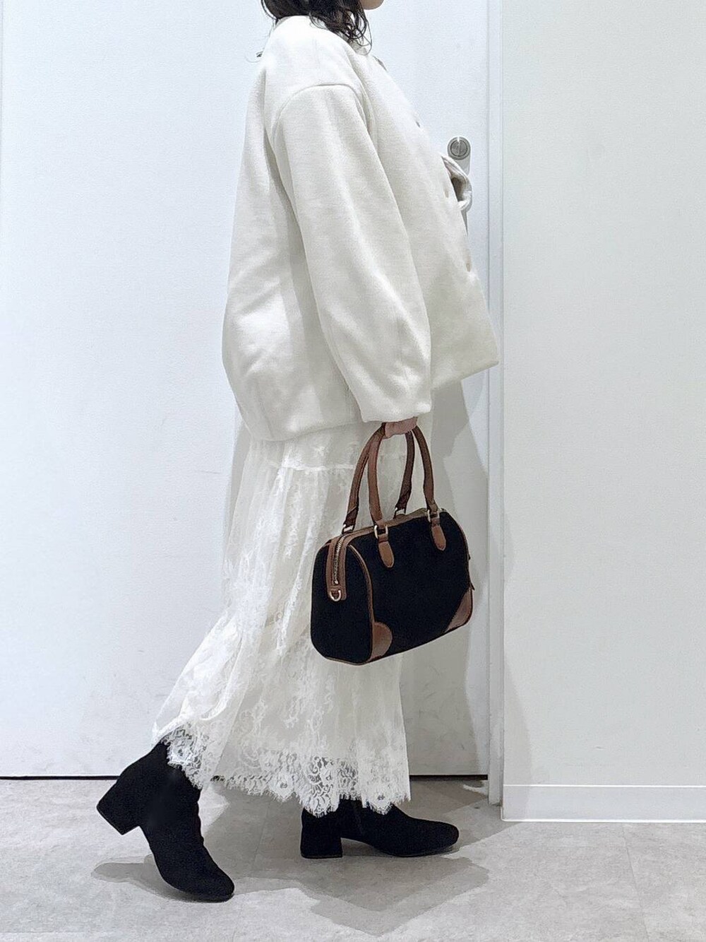 ベージュ系のノーカラーコート、グレー系のワンピース、ブラック系のボストンバッグを着用したレディースの秋コーディネートの2枚目の写真