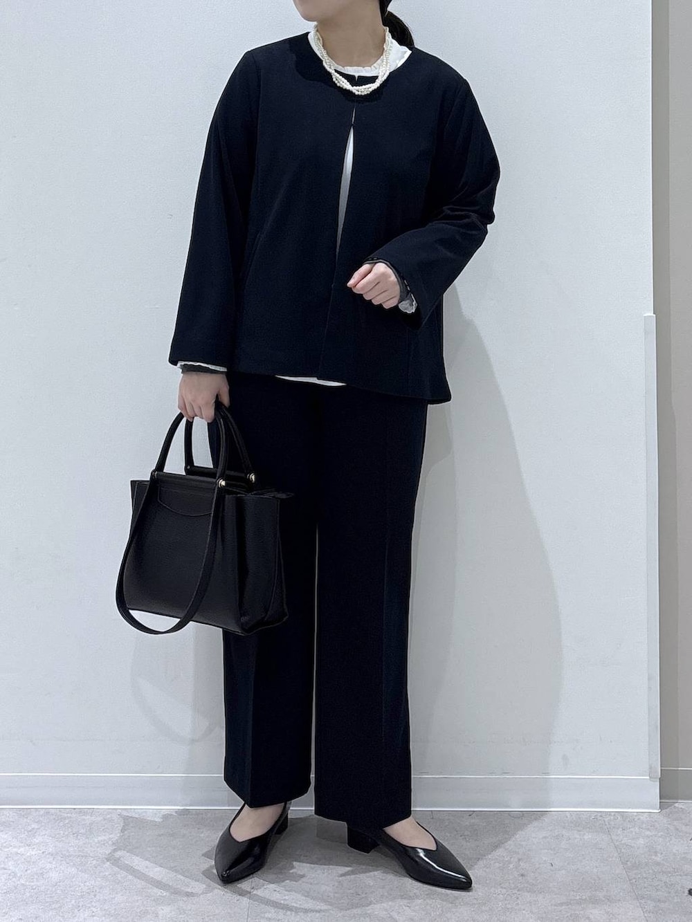 ブラック系のパンプス、ブルー系のセットアップ、ブラック系のトートバッグを着用したレディースの冬コーディネートの4枚目の写真