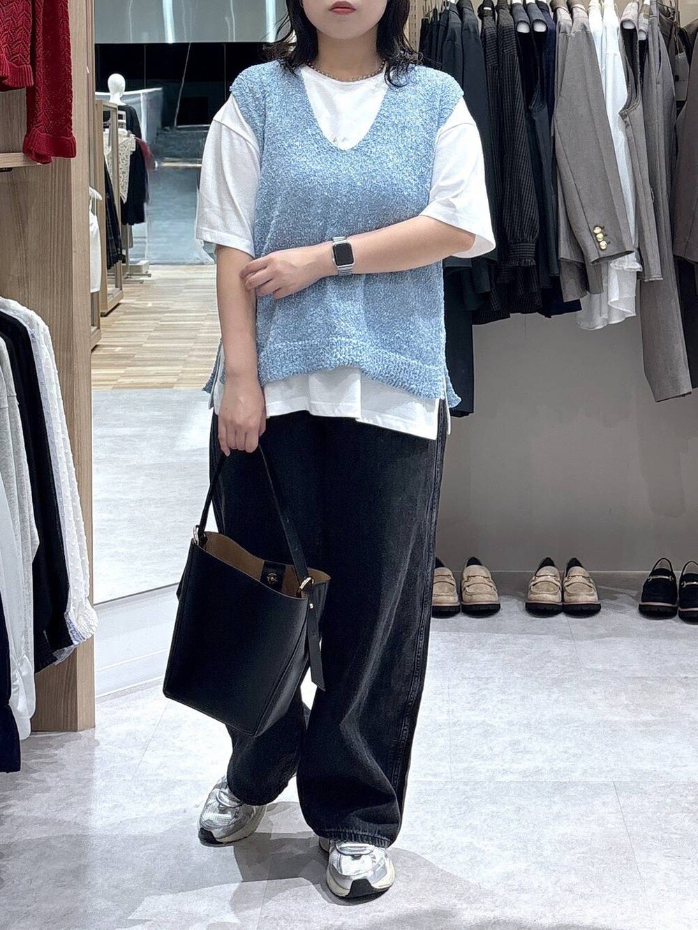 ブラック系のショルダーバッグ、ブルー系のTシャツ/カットソー、ブラック系のデニムパンツを着用したレディースの秋コーディネートの3枚目の写真