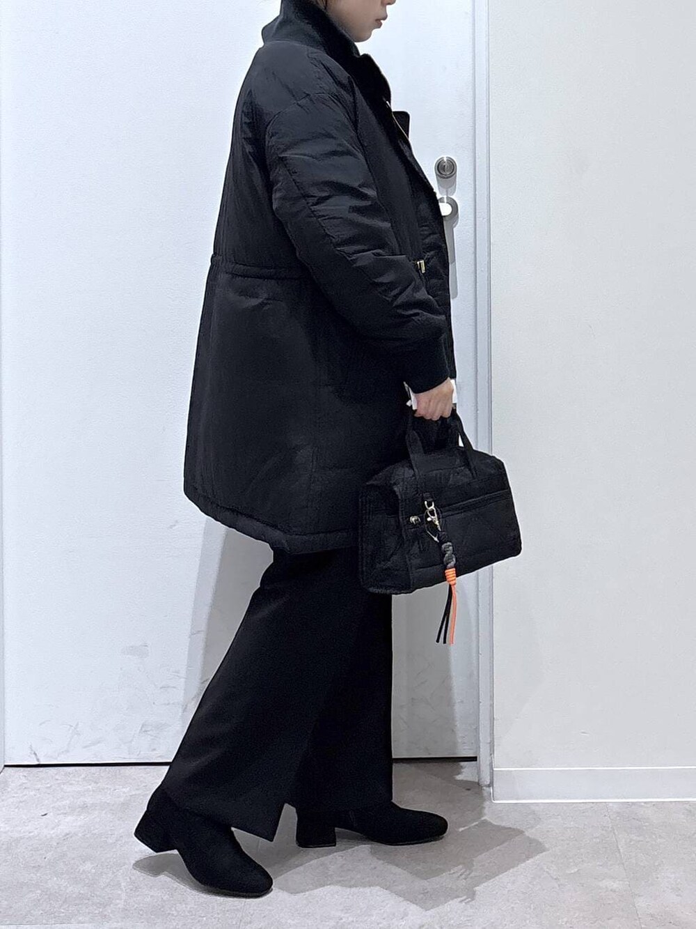 ブラック系のダウンジャケット/コート、ブラック系のボストンバッグ、ブルー系のニット/セーターを着用したレディースの冬コーディネートの2枚目の写真